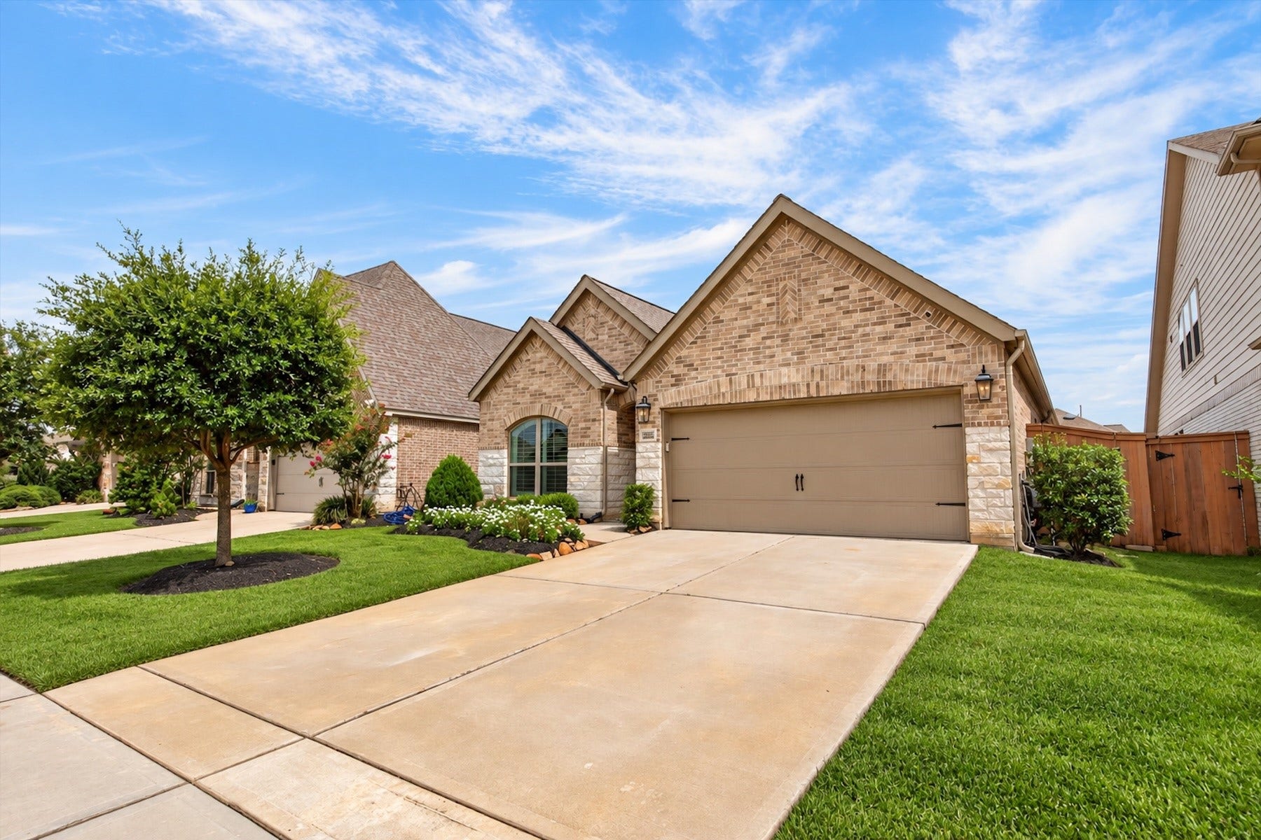 23026 Needlegrass Road, Katy, TX 77493 Spacious driveway, two-car garage, and charming brick-and-stone elevation.