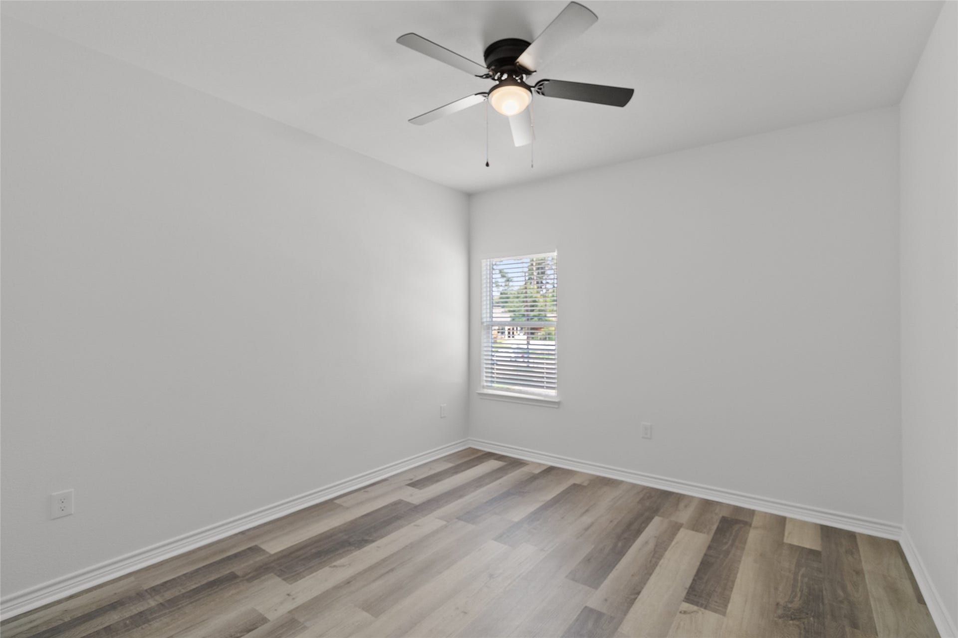 760 Juneau Court, Montgomery, TX 77316 This is a bright, modern room with fresh white walls and contemporary wood-look flooring. It features a ceiling fan with a lighting fixture and a window that allows for natural light.
