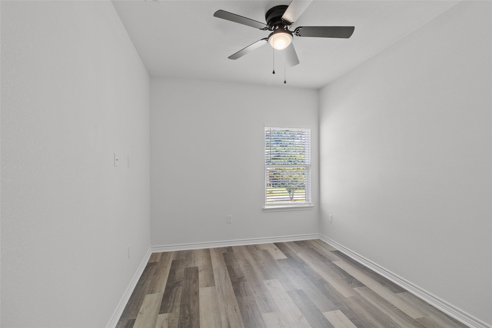 760 Juneau Court, Montgomery, TX 77316 This is a bright, neutral-toned room with modern laminate flooring and a ceiling fan with a light fixture. There's a single window providing natural light.