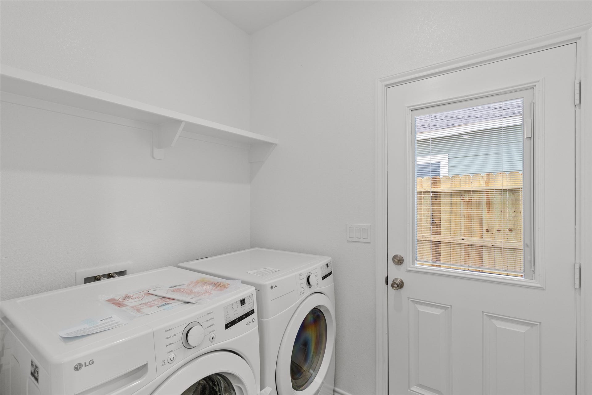 760 Juneau Court, Montgomery, TX 77316 This photo shows a compact, neatly maintained laundry room with modern appliances, a convenient shelf for storage, and natural light from a window.