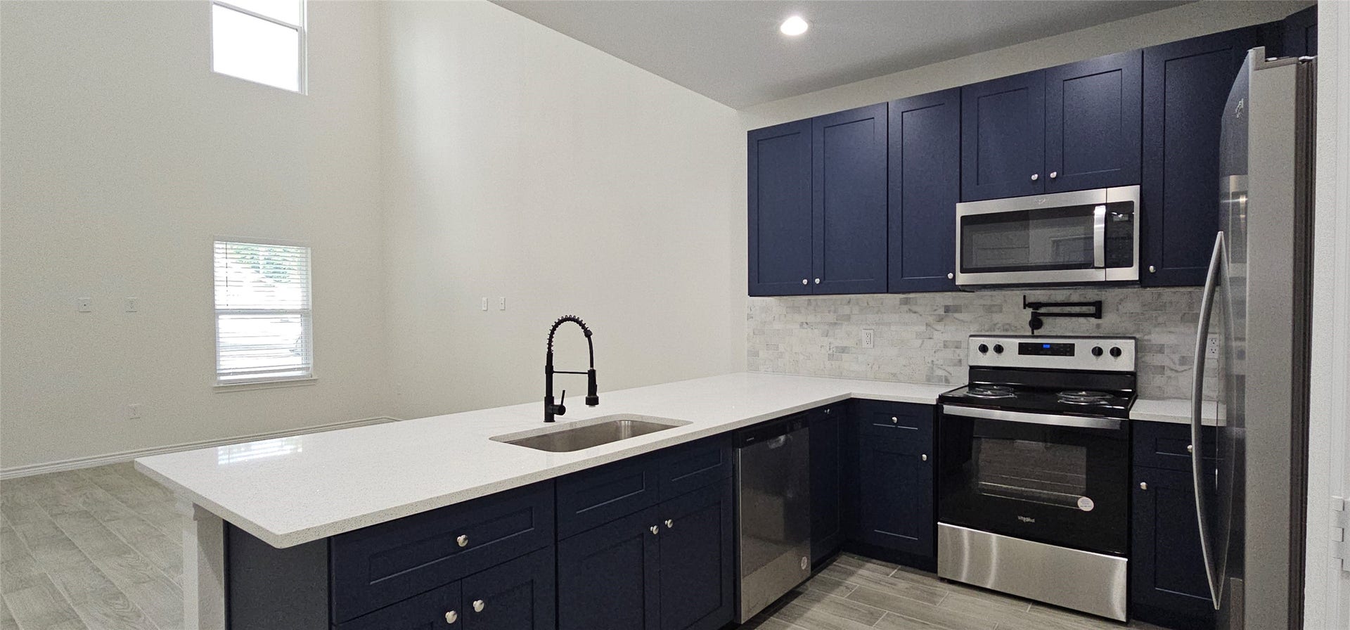 760 Juneau Court, Montgomery, TX 77316 Modern kitchen with high ceilings, stainless steel appliances, dark blue cabinetry, and light countertops with a huge breakfast bar.