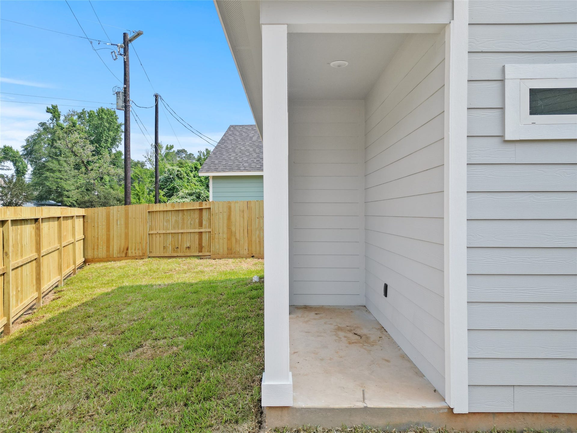760 Juneau Court, Montgomery, TX 77316 This image showcases a home's side yard featuring a well-maintained wooden fence for privacy, a small concrete patio area, and a freshly cut grass lawn. The exterior wall of the house is finished with clean, white siding.
