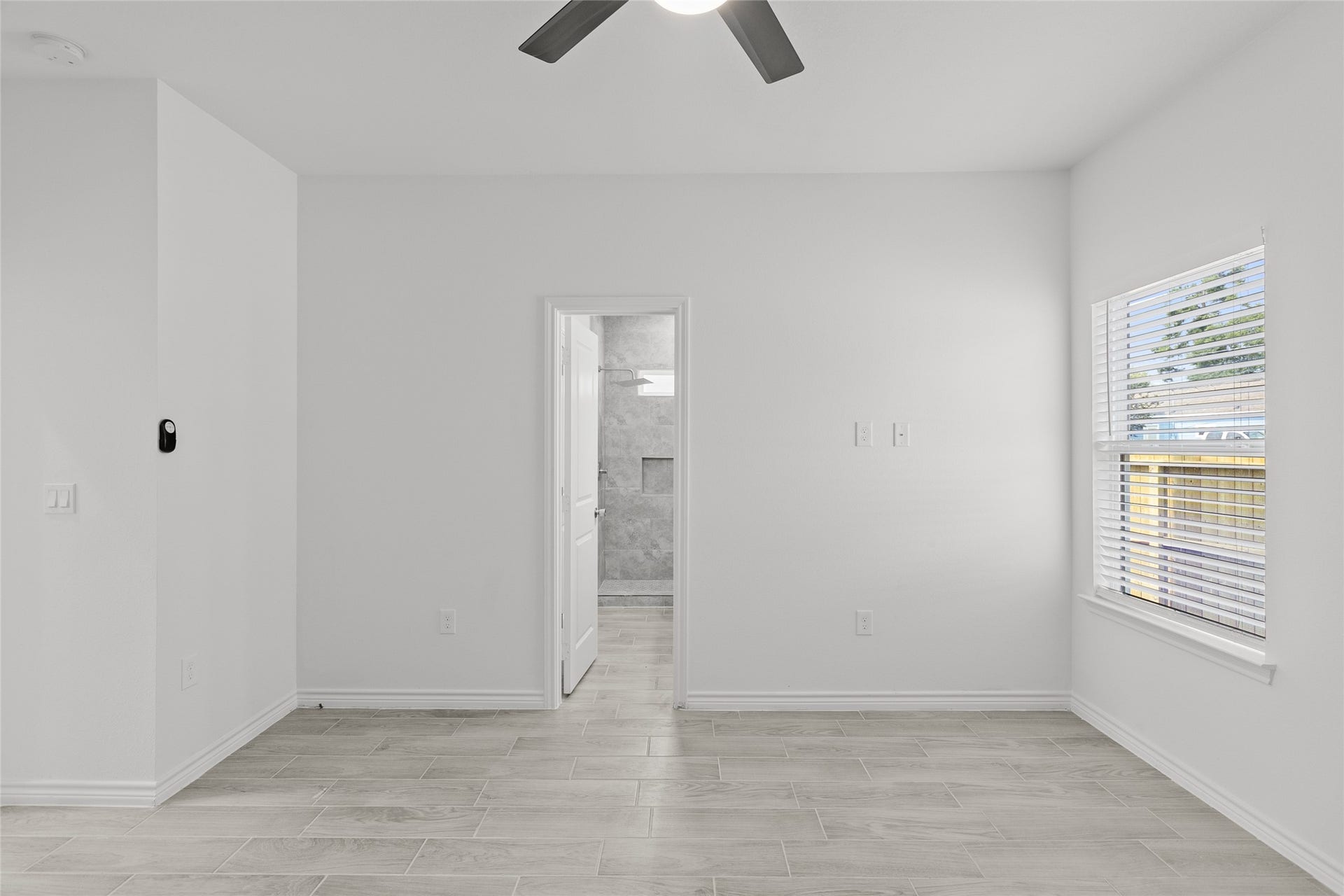 760 Juneau Court, Montgomery, TX 77316 This is a bright, modern room with fresh white walls, large window for natural light, and sleek tile flooring, leading to an en-suite bathroom.
