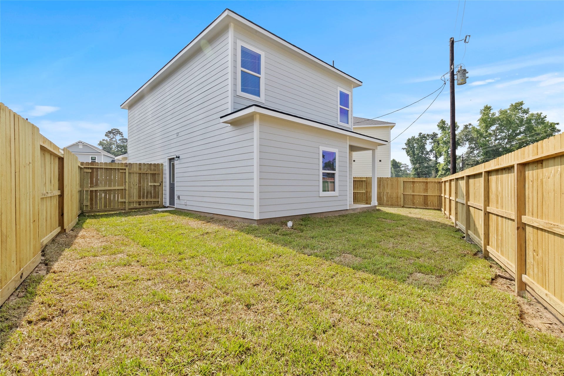 760 Juneau Court, Montgomery, TX 77316 This is a photo of the exterior of a two-story home featuring a fresh, natural grass lawn enclosed by a new wooden privacy fence. The house has a modern design with clean lines and a neutral color palette.