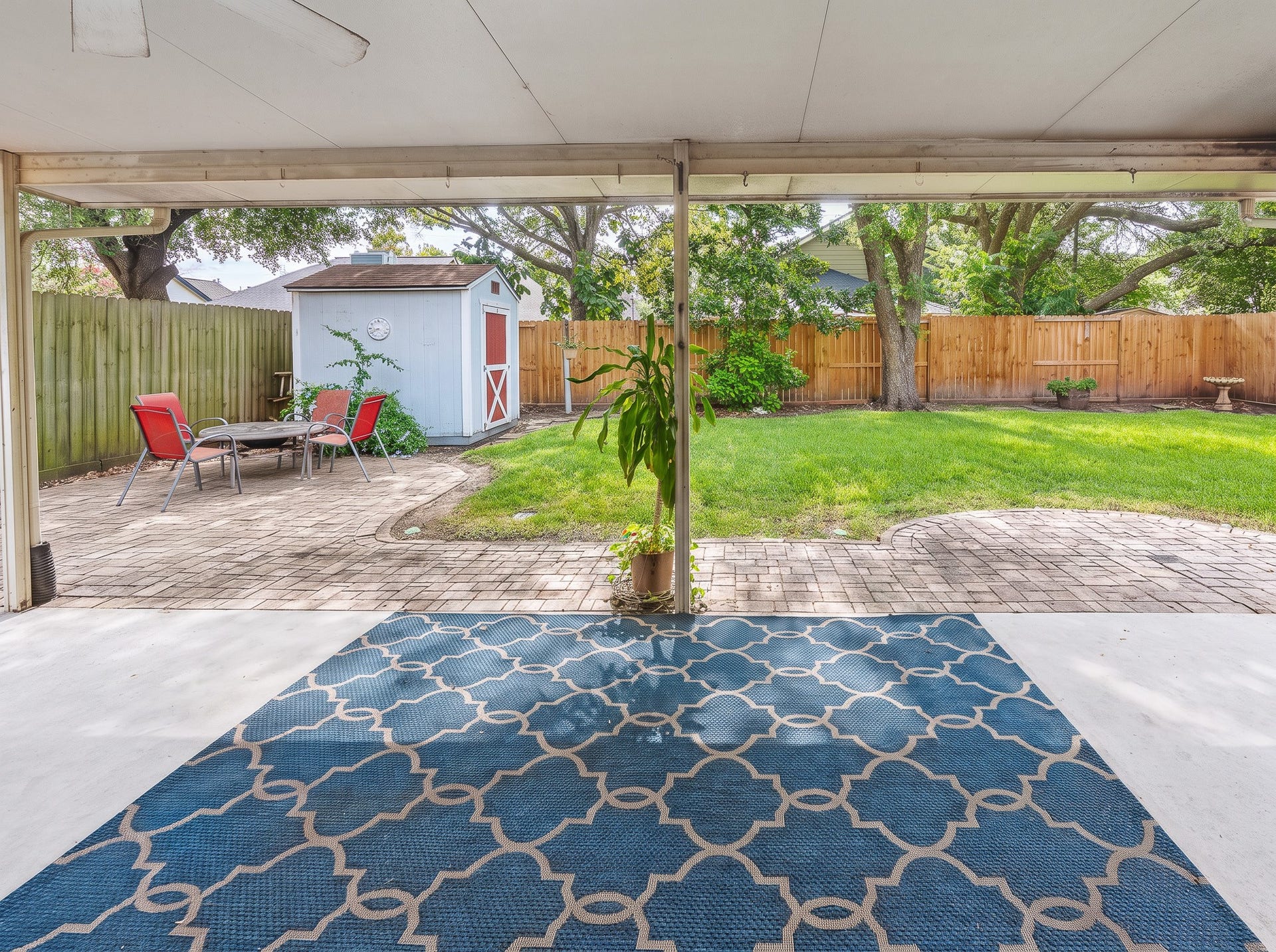 1118 Wentworth Drive, Pearland, TX 77584 A covered patio provides easy access to the lush backyard, where a paved seating area, outdoor storage shed, and fire pit create a versatile setting for outdoor relaxation.