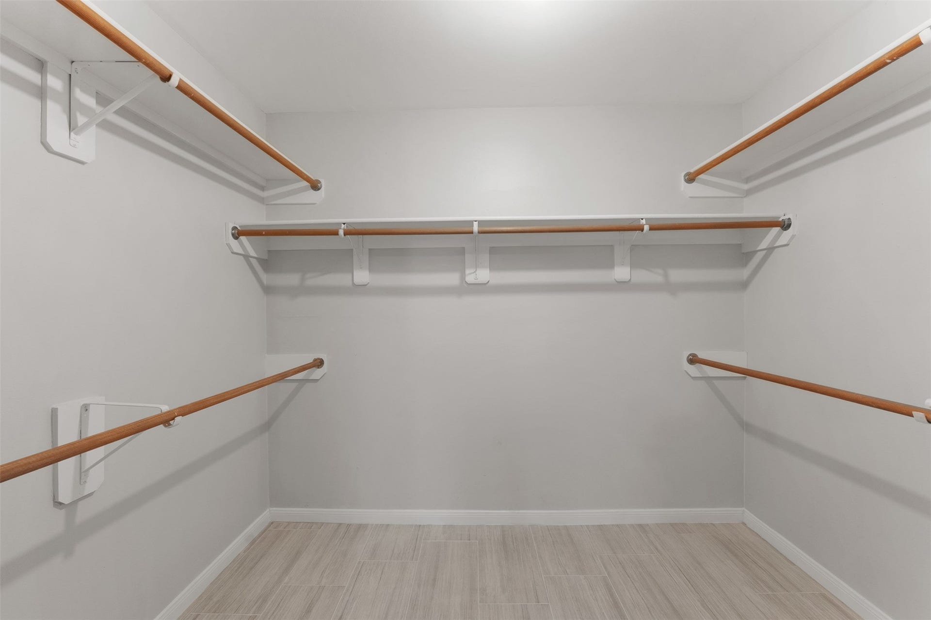 1118 Wentworth Drive, Pearland, TX 77584 Multi-level wooden hanging rods and built-in shelving maximize organization in this spacious walk-in closet. Soft light-toned wood flooring completes the functional storage space.