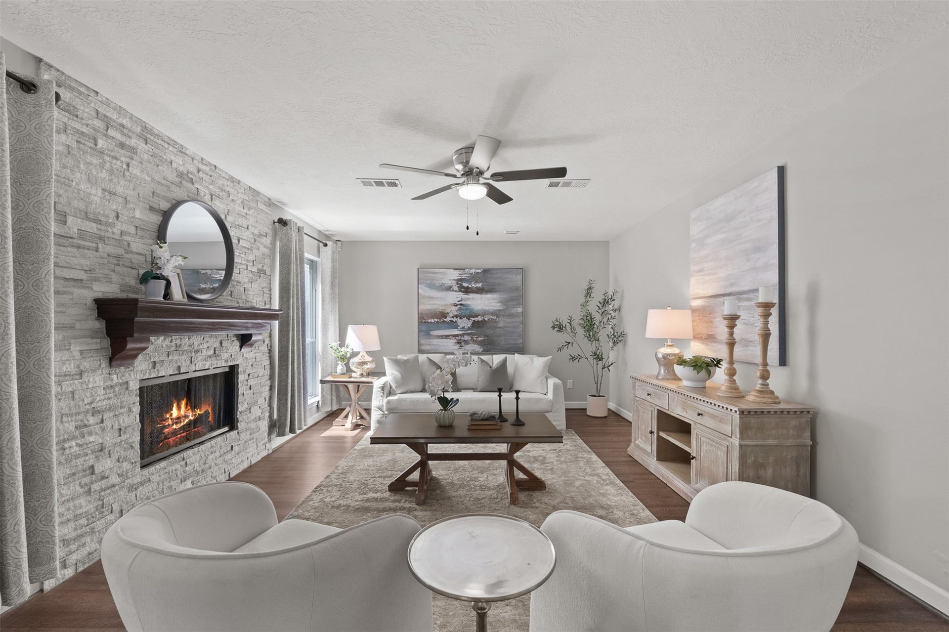1118 Wentworth Drive, Pearland, TX 77584 A floor-to-ceiling stone stack fireplace anchors this inviting living space, accented by warm wood flooring and a classic ceiling fan. Soaring natural light streams in from surrounding windows, highlighting an open layout ideal for relaxed hosting.