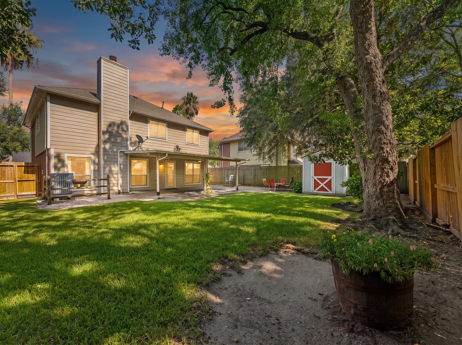 1118 Wentworth Drive, Pearland, TX 77584 Shaded by magnificent trees, this expansive grassy backyard features a covered patio, paved seating area, full privacy fencing, and a distinctive red storage shed.