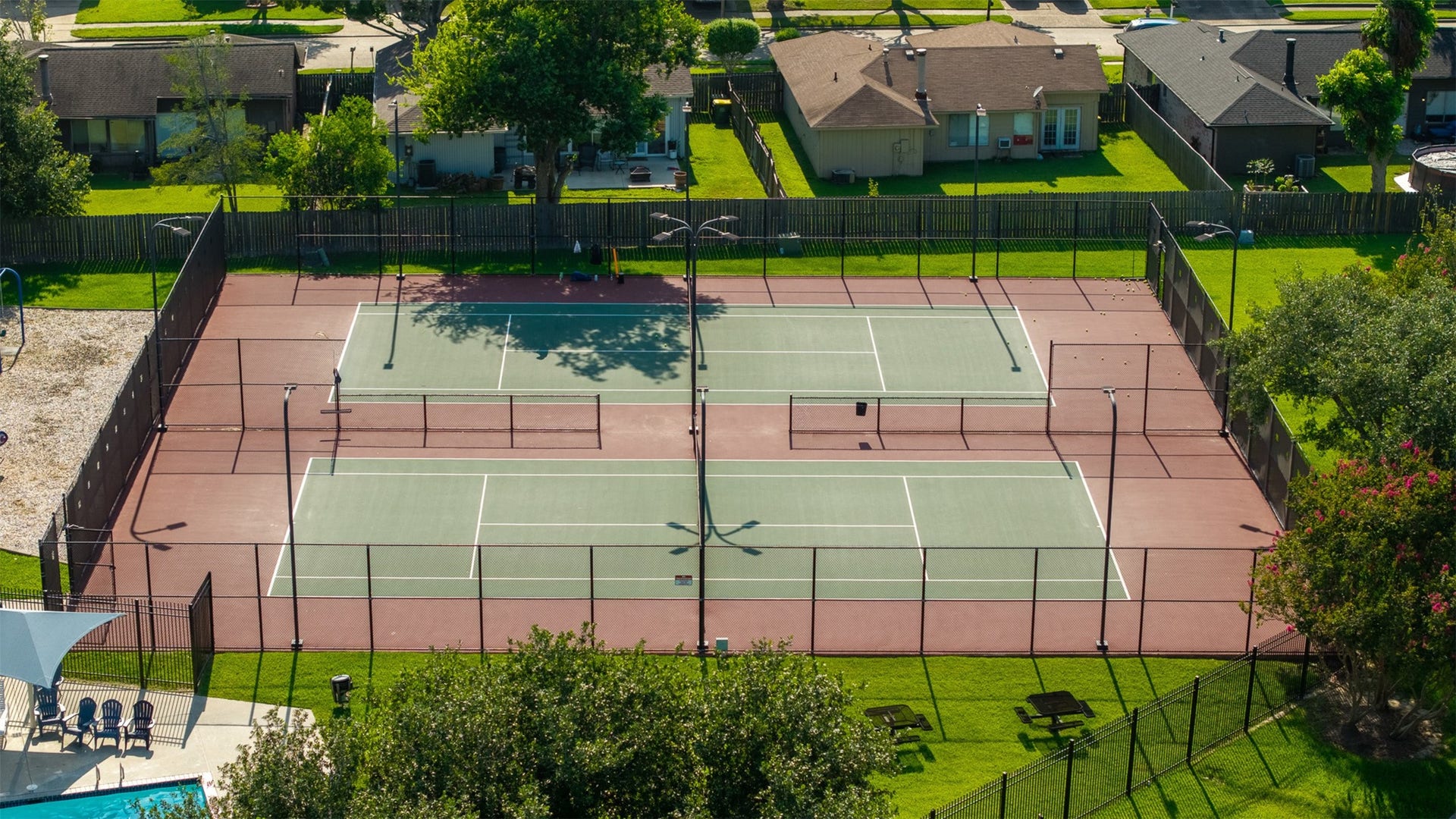 1118 Wentworth Drive, Pearland, TX 77584 Surrounded by manicured green spaces and tall fencing, this community sports court features two full-sized tennis courts equipped with overhead lighting. Residents enjoy premier recreation options steps away, alongside access to a nearby community pool.