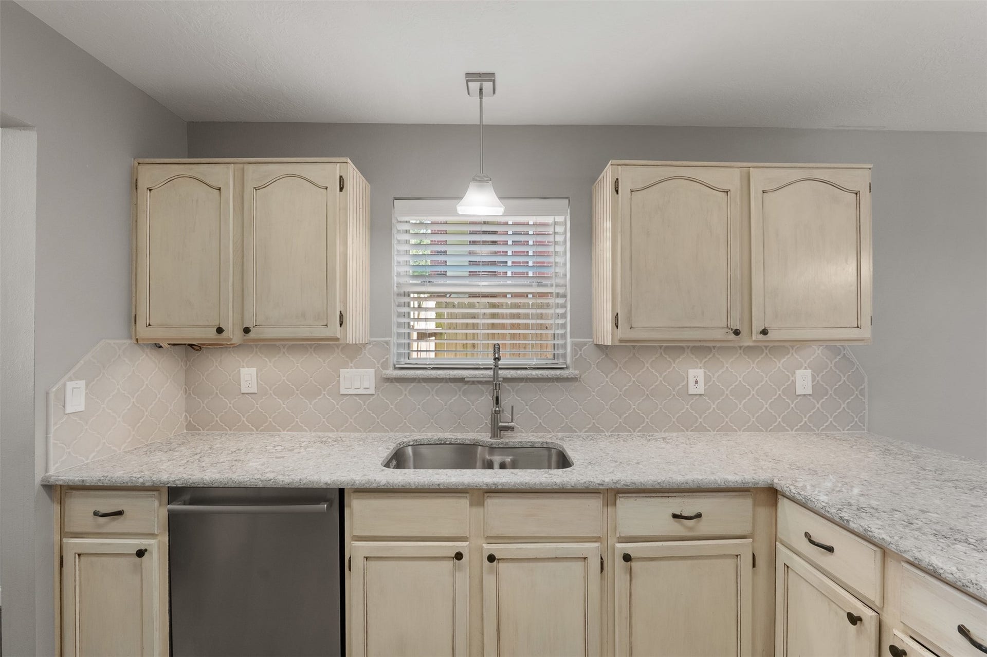 1118 Wentworth Drive, Pearland, TX 77584 Quartz countertops, a intricate designer backsplash, and a spacious dual sink anchored under a window refine this culinary space. Off-white cabinetry offers ample storage, complimented by sleek stainless steel appliances and a modern pendant light.