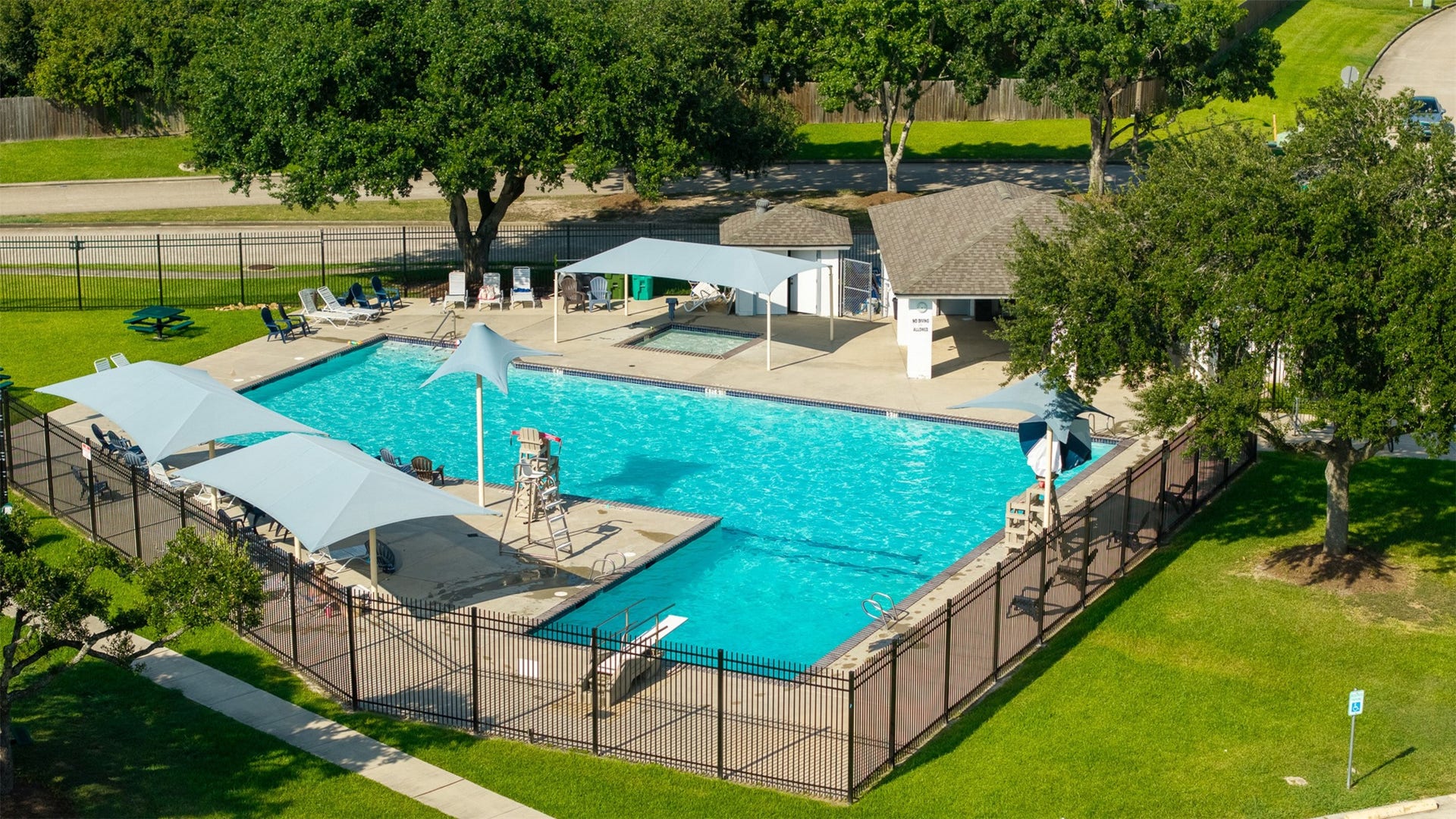 1118 Wentworth Drive, Pearland, TX 77584 High-angle aerial capture showcases the expansive community pool area, complete with a shade canopy, lounge seating, and an adjacent splash pad. Residents enjoy this premier neighborhood amenity along with nearby sports courts and parks.