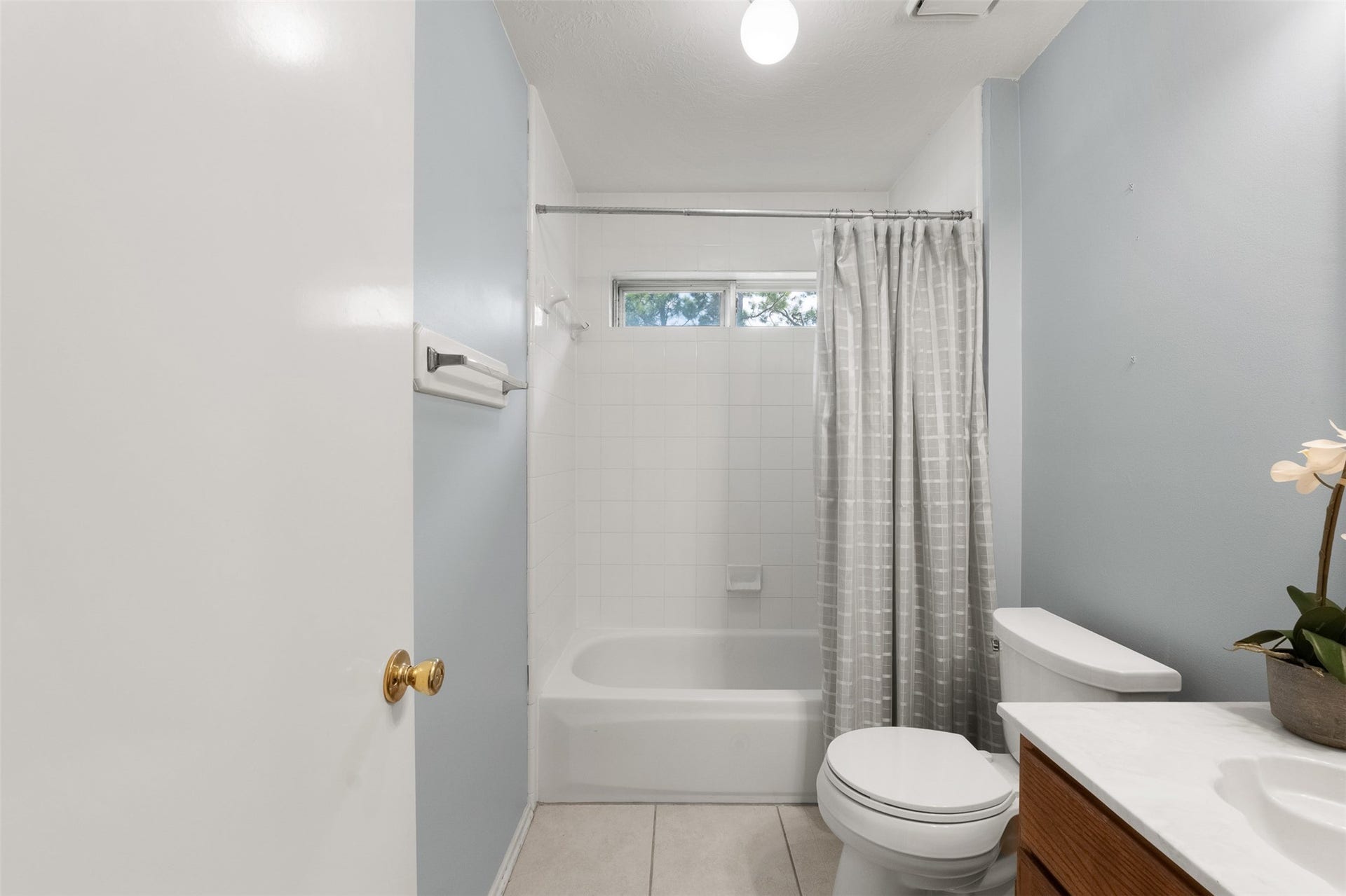 1118 Wentworth Drive, Pearland, TX 77584 A light blue accent wall and crisp tile flooring bring a fresh look to this secondary bath. Renovated features include a classic tub-and-shower combo, modern vanity, and a transom window that lets in gentle light.