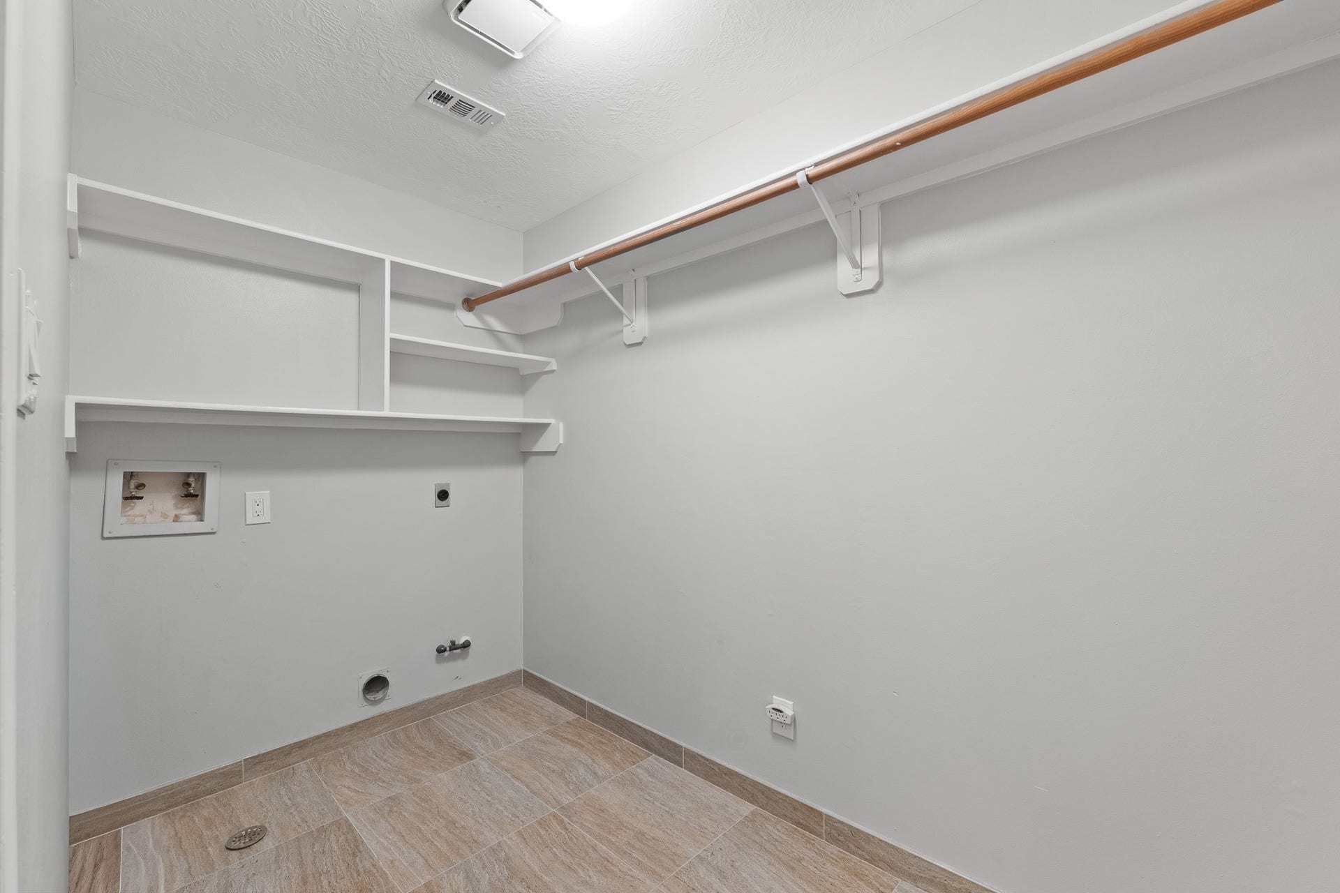 1118 Wentworth Drive, Pearland, TX 77584 Tile flooring and built-in shelving enhance this functional laundry room, offering overhead clothes rods and hookups.