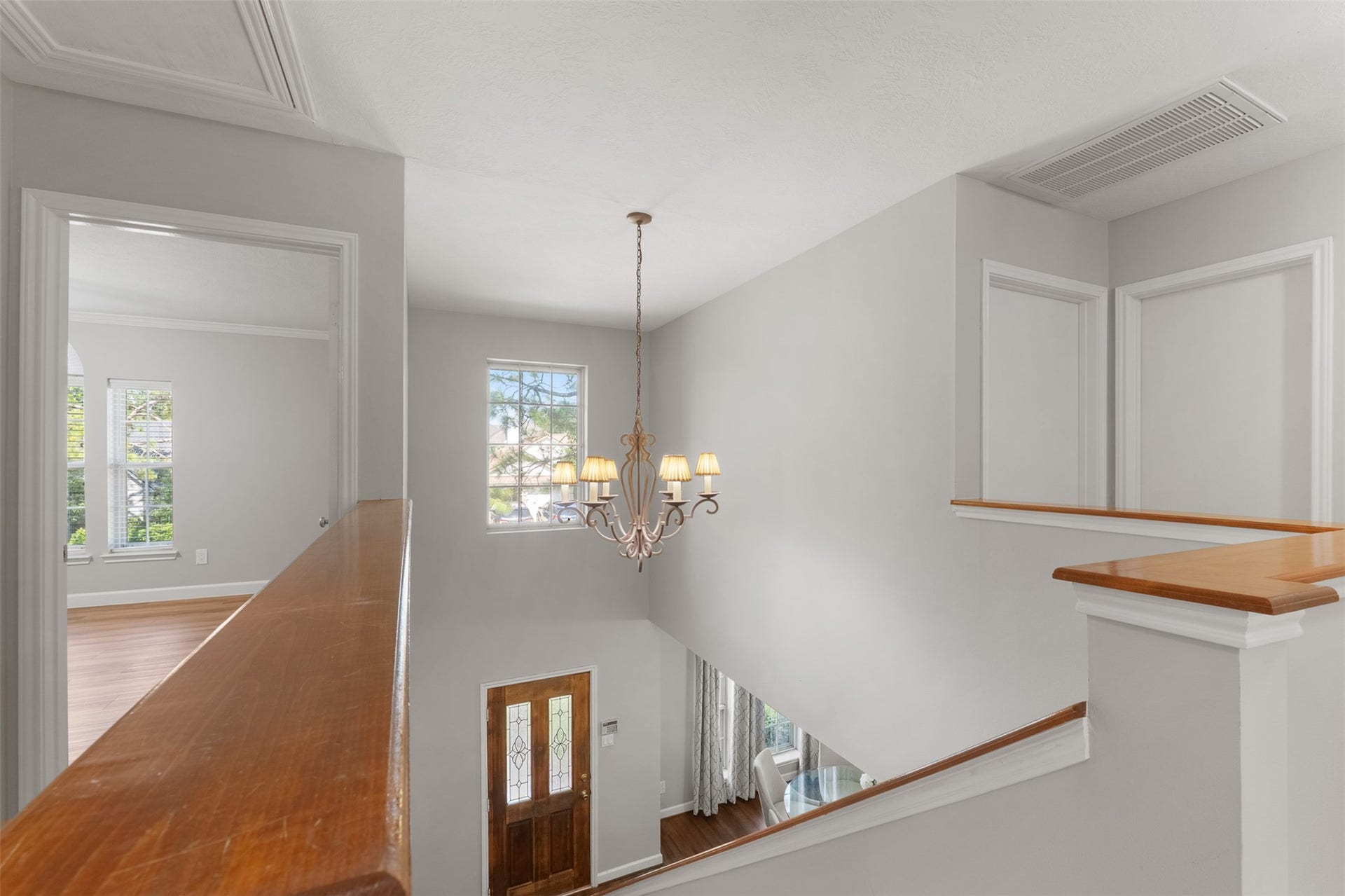 1118 Wentworth Drive, Pearland, TX 77584 A classic chandelier suspends over the multi-story entry, illuminating the open second-floor hallway and stairwell. Neutral wall paint and wood-topped railings unite the upper landing with views of the lower level below.