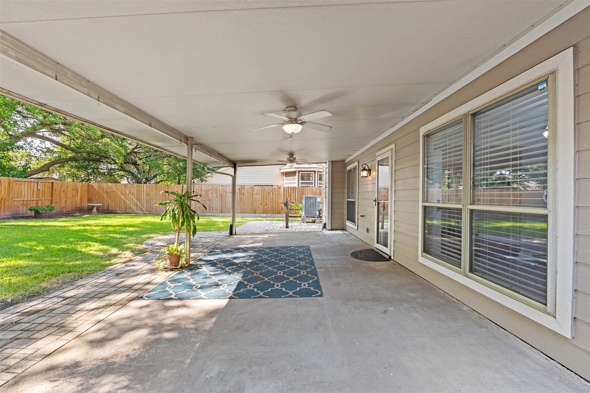 1118 Wentworth Drive, Pearland, TX 77584 Extending from the home's rear exterior, a deep covered patio equipped with dual ceiling fans overlooks the expansive backyard lawn and paver patio. Large windows and a glass-paneled back door provide easy access and uninterrupted sightlines to the interior living spaces.