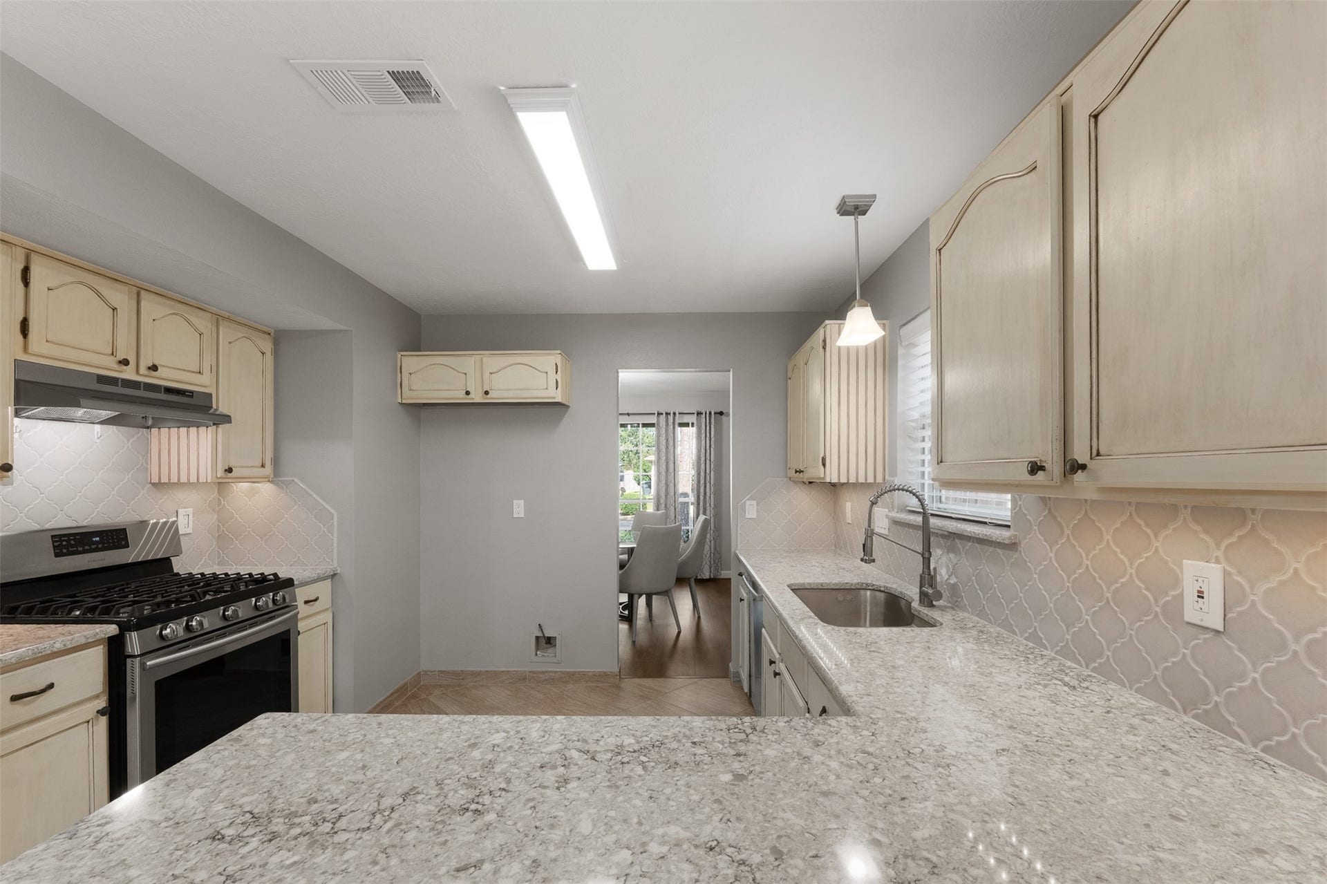 1118 Wentworth Drive, Pearland, TX 77584 Equipped with a gas range and spacious dual sink, this kitchen showcases quartz countertops and a designer backsplash. Cream cabinetry provides ample storage, while the expansive counter extends into a functional breakfast bar.