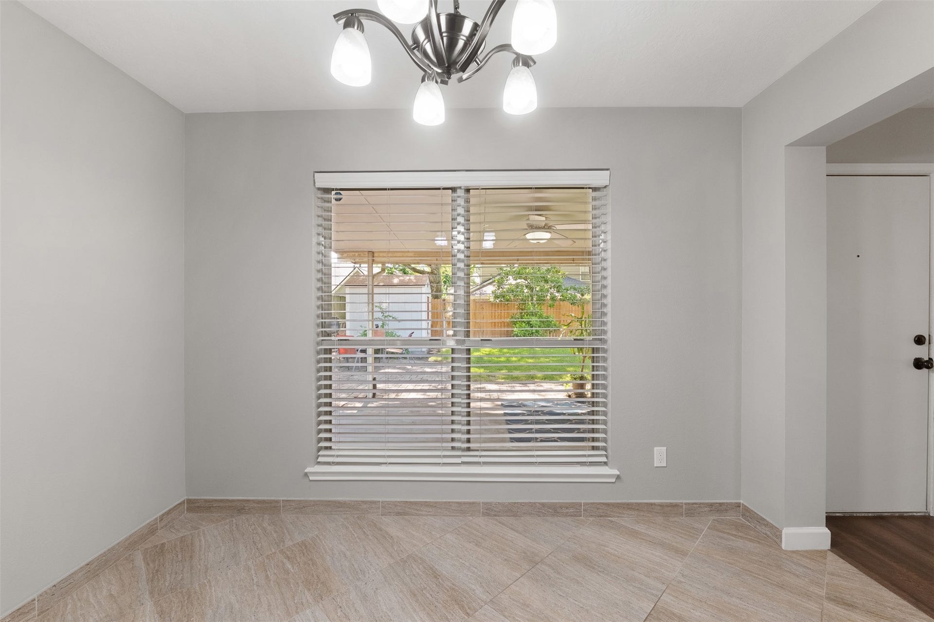 1118 Wentworth Drive, Pearland, TX 77584 Positioned directly off the kitchen, this sunlit breakfast nook showcases diagonal tile flooring and a brushed nickel chandelier. A expansive window framed with blinds overlooks the covered patio and lush backyard, offering a serene backdrop for morning meals.