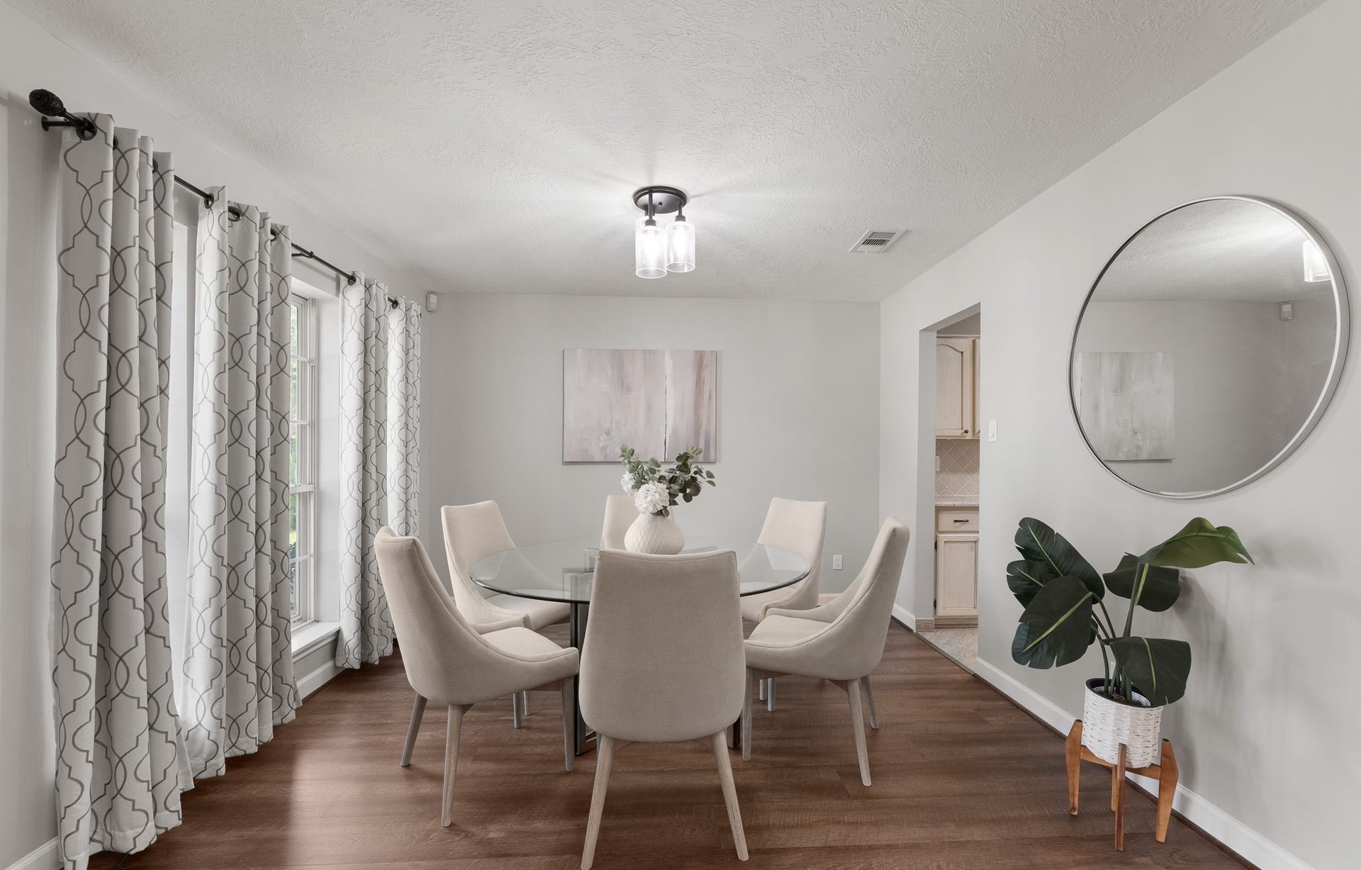 1118 Wentworth Drive, Pearland, TX 77584 Sunlight streams through large windows into this refined formal dining room, highlighting rich wood-look flooring and a modern light fixture. The open layout accommodates a six-person table while offering seamless access to the adjacent kitchen.