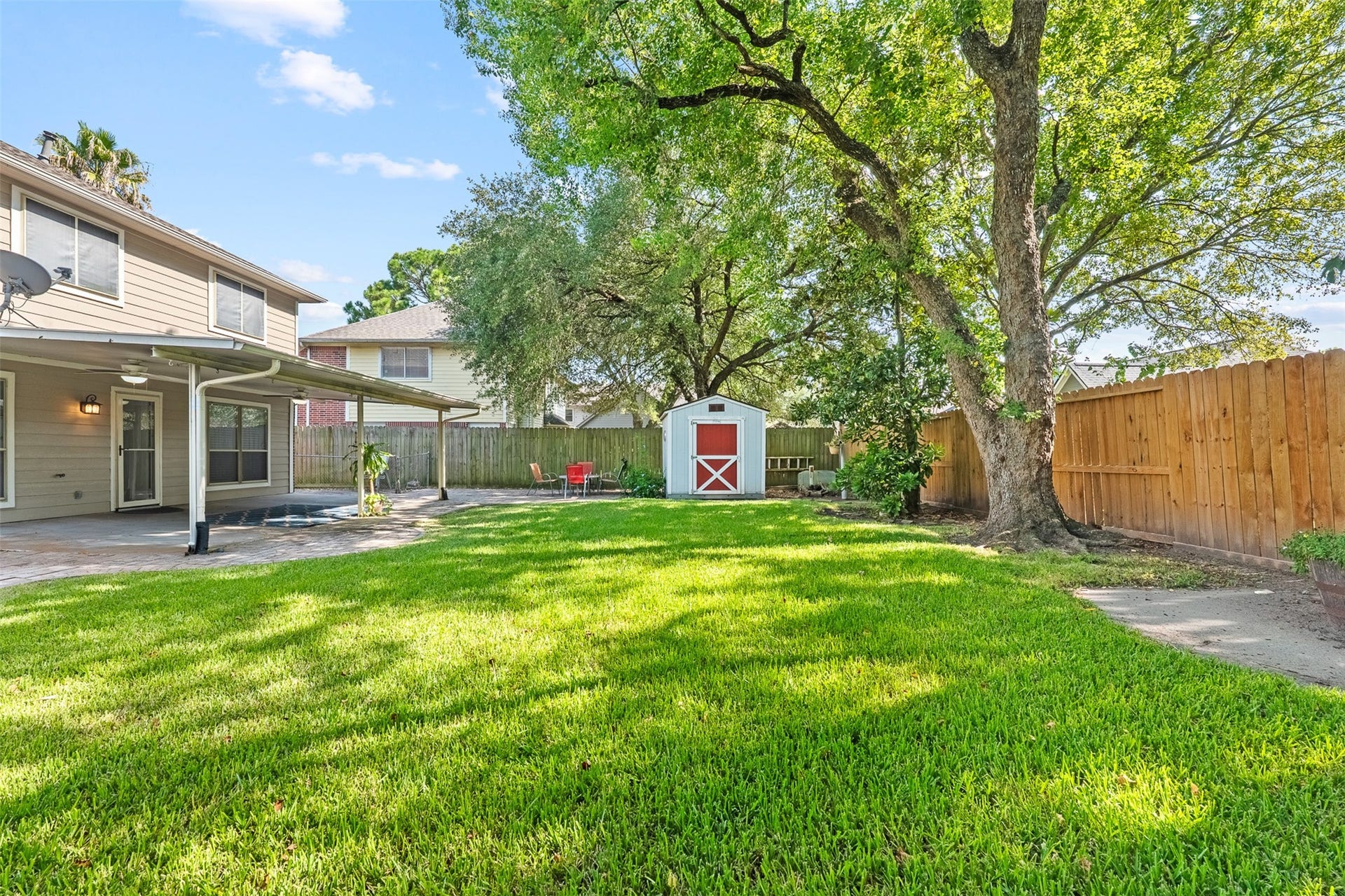 1118 Wentworth Drive, Pearland, TX 77584 Expansive green lawn stretches past a classic red storage shed, towering shade trees, and a full privacy fence in this tranquil backyard. A paver extension off the covered patio provides easy access for outdoor entertaining and relaxation.