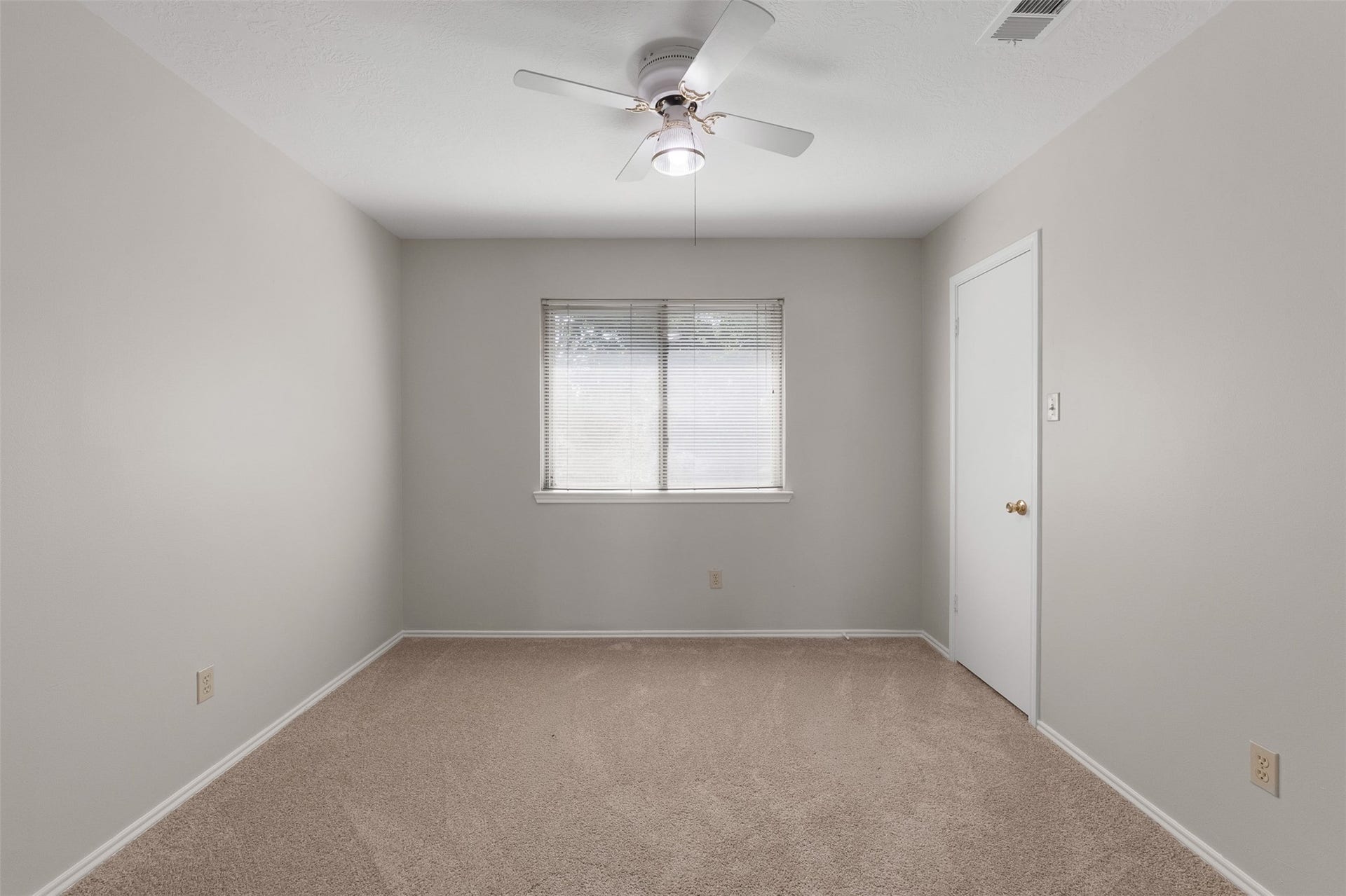 1118 Wentworth Drive, Pearland, TX 77584 Neutral walls and cozy carpet flooring define this secondary bedroom, anchored by a central window with blinds. A traditional ceiling fan provides comfortable illumination, while fresh interior paint creates a bright atmosphere.