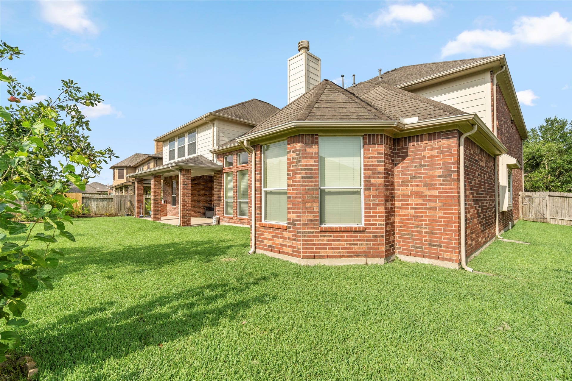 5307 Amber Sky Lane, Rosharon, TX 77583 The elegant all-brick exterior continues seamlessly into the backyard, showcasing timeless architecture against a backdrop of manicured greenery.