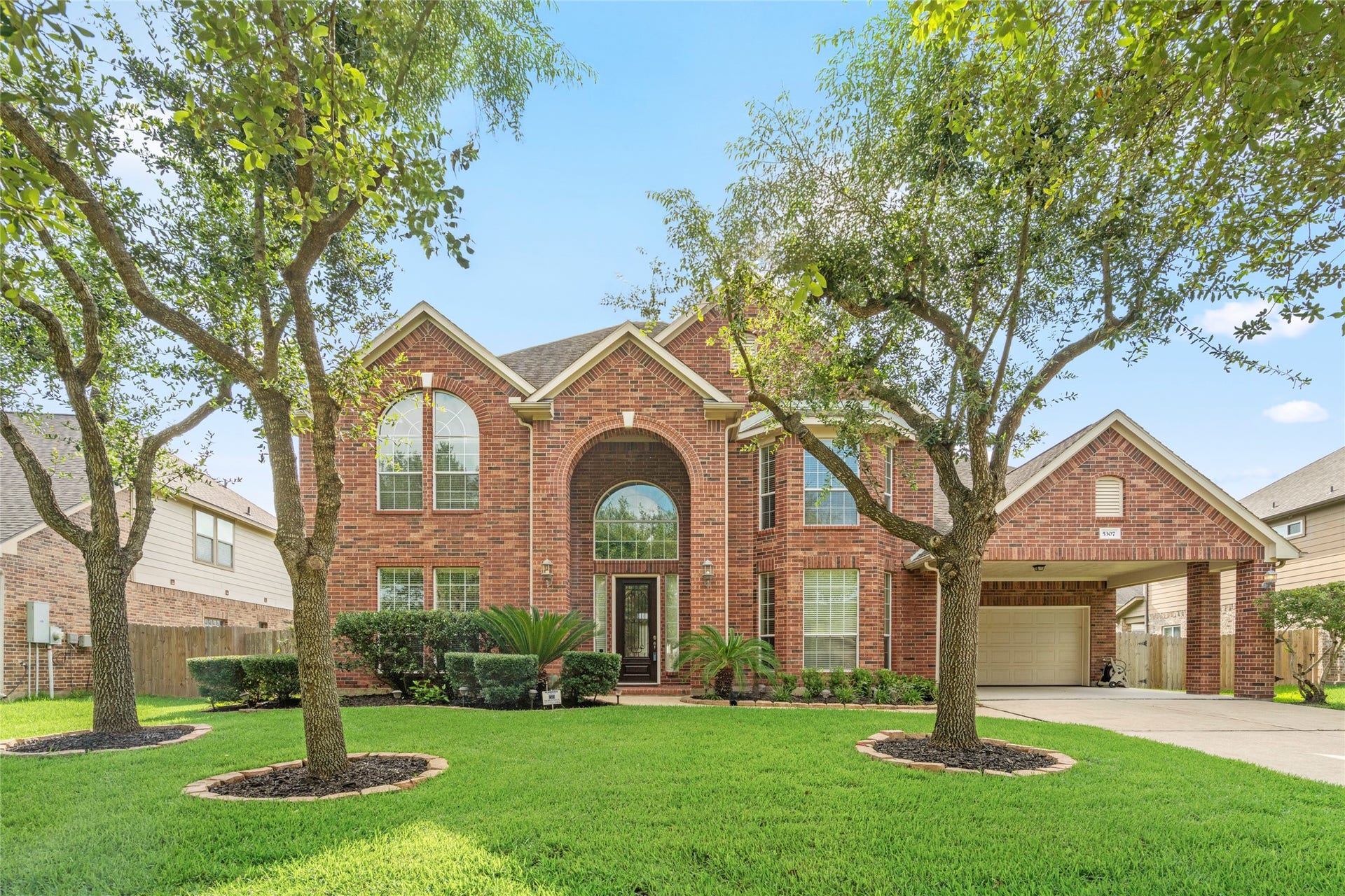 5307 Amber Sky Lane, Rosharon, TX 77583 Bathed in daylight, this elegant brick residence showcases manicured landscaping, a grand arched entry, and abundant natural light pouring through oversized windows, a welcoming first impression for the most discerning buyer.