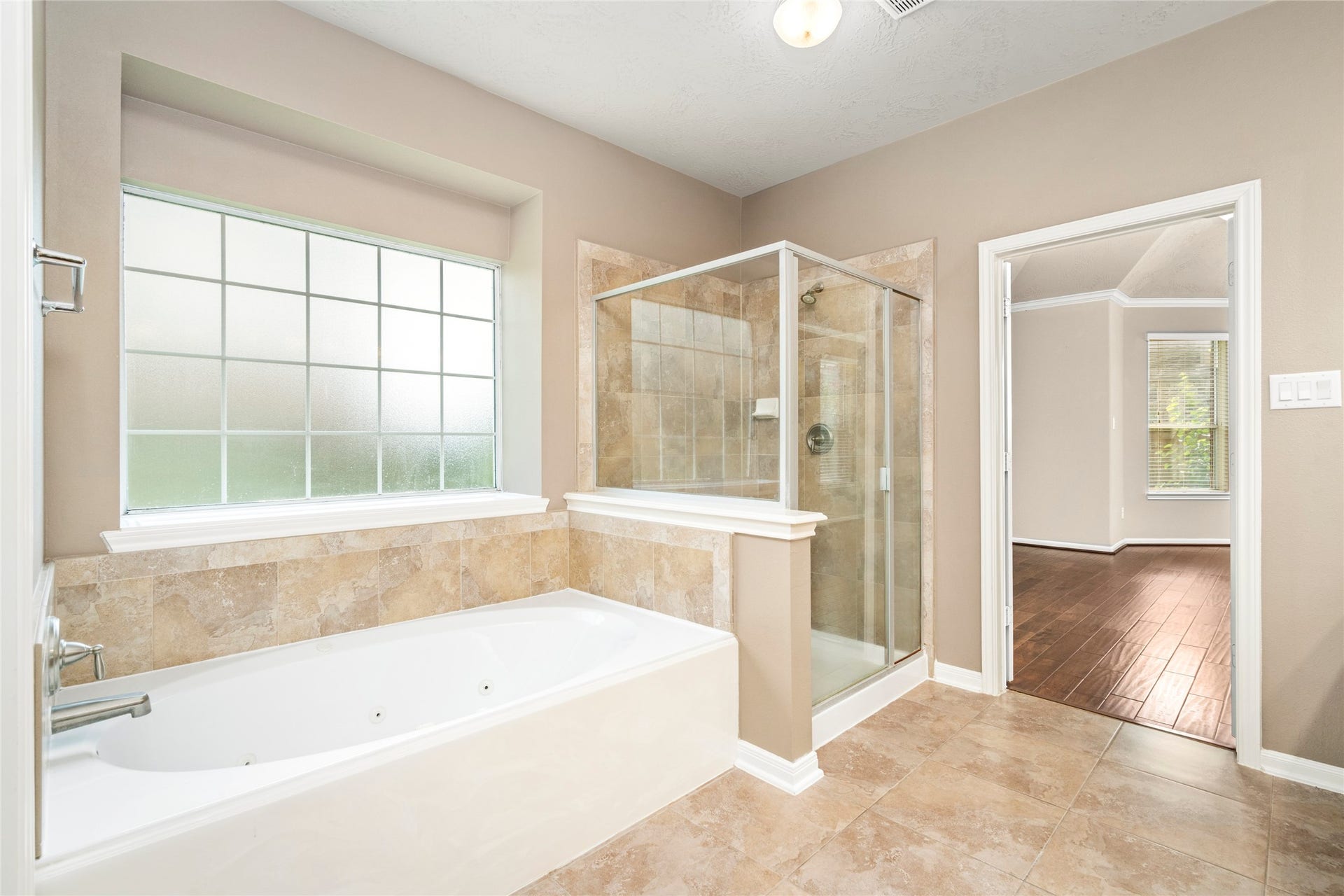 5307 Amber Sky Lane, Rosharon, TX 77583 An oversized standalone jetted soaking tub and glass-enclosed shower anchor this spa-caliber primary bath, with elegant tile flooring and a frosted window inviting natural light while preserving privacy.