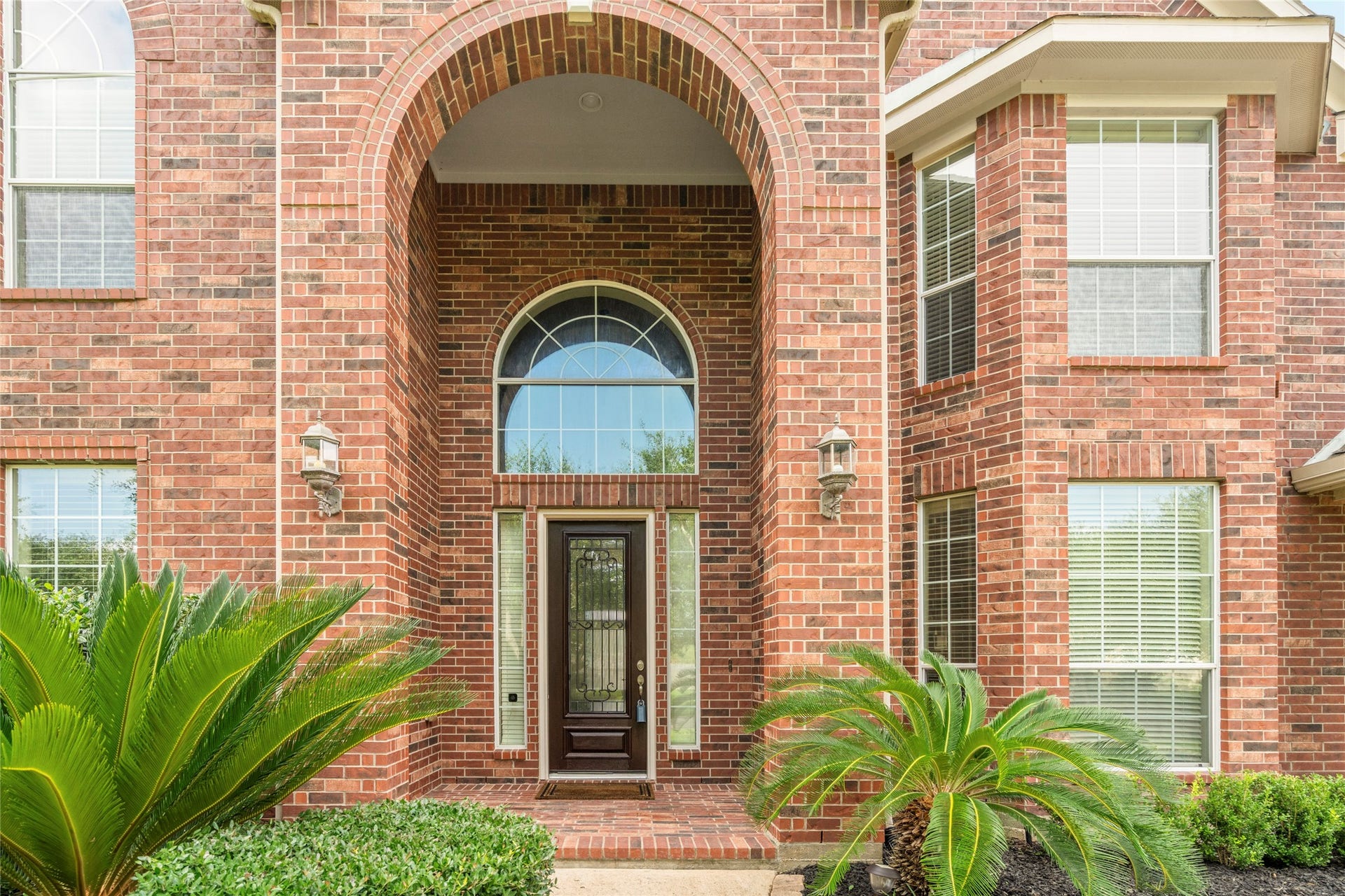 5307 Amber Sky Lane, Rosharon, TX 77583 A breathtaking arched brick entryway sets a grand tone from the curb, framing a stately wood and wrought-iron front door beneath a sweeping arched transom window striking craftsmanship and elegant landscaping welcome you home.