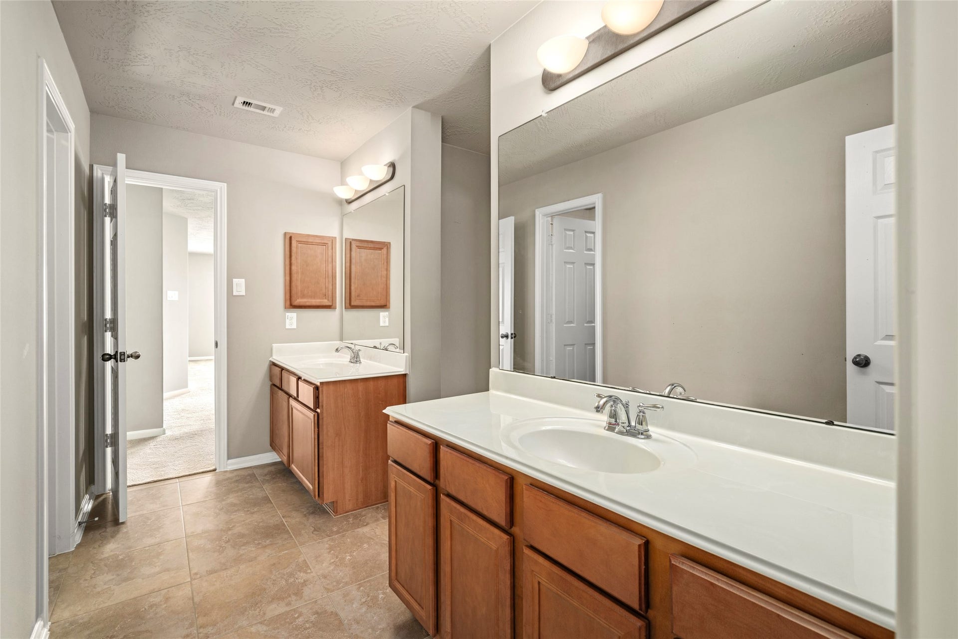 5307 Amber Sky Lane, Rosharon, TX 77583 A spacious double-vanity bath with rich wood cabinetry, oversized mirrors, and tile flooring serves the upstairs bedrooms with style and function.