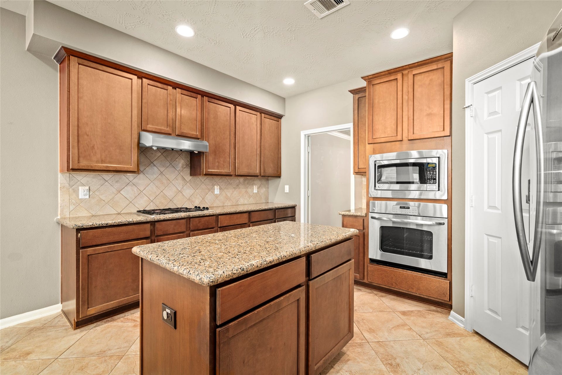 5307 Amber Sky Lane, Rosharon, TX 77583 Rich wood cabinetry, granite counters, and a spacious center island define this exceptional kitchen, thoughtfully designed as the true heart of the home.