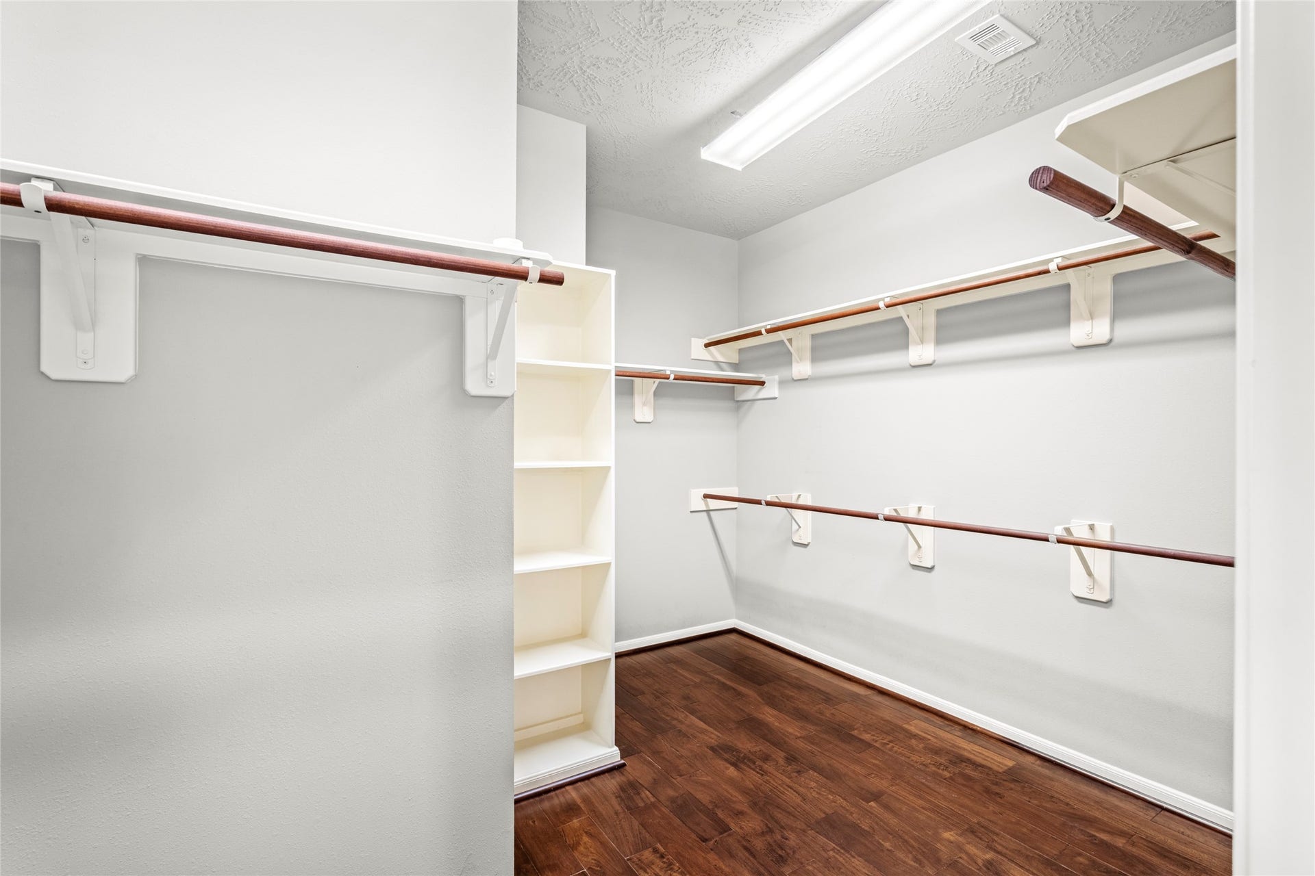 5307 Amber Sky Lane, Rosharon, TX 77583 The oversized primary walk-in closet features rich wood flooring and generous hanging storage, closet space designed with the discerning homeowner in mind.