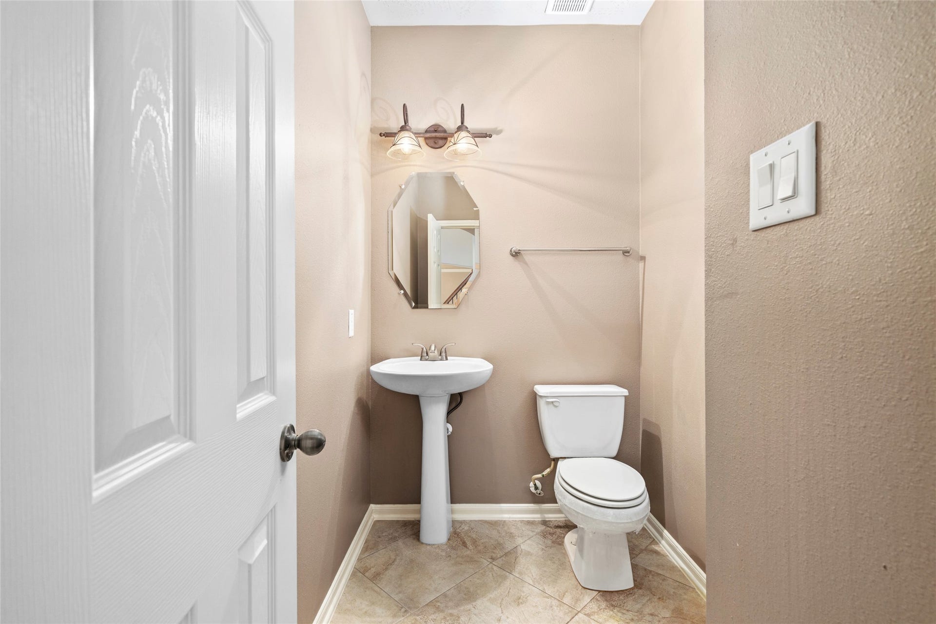 5307 Amber Sky Lane, Rosharon, TX 77583 A chic powder bath welcomes guests with a graceful pedestal sink, designer octagonal mirror, and warm tile flooring, refined convenience on the main floor.
