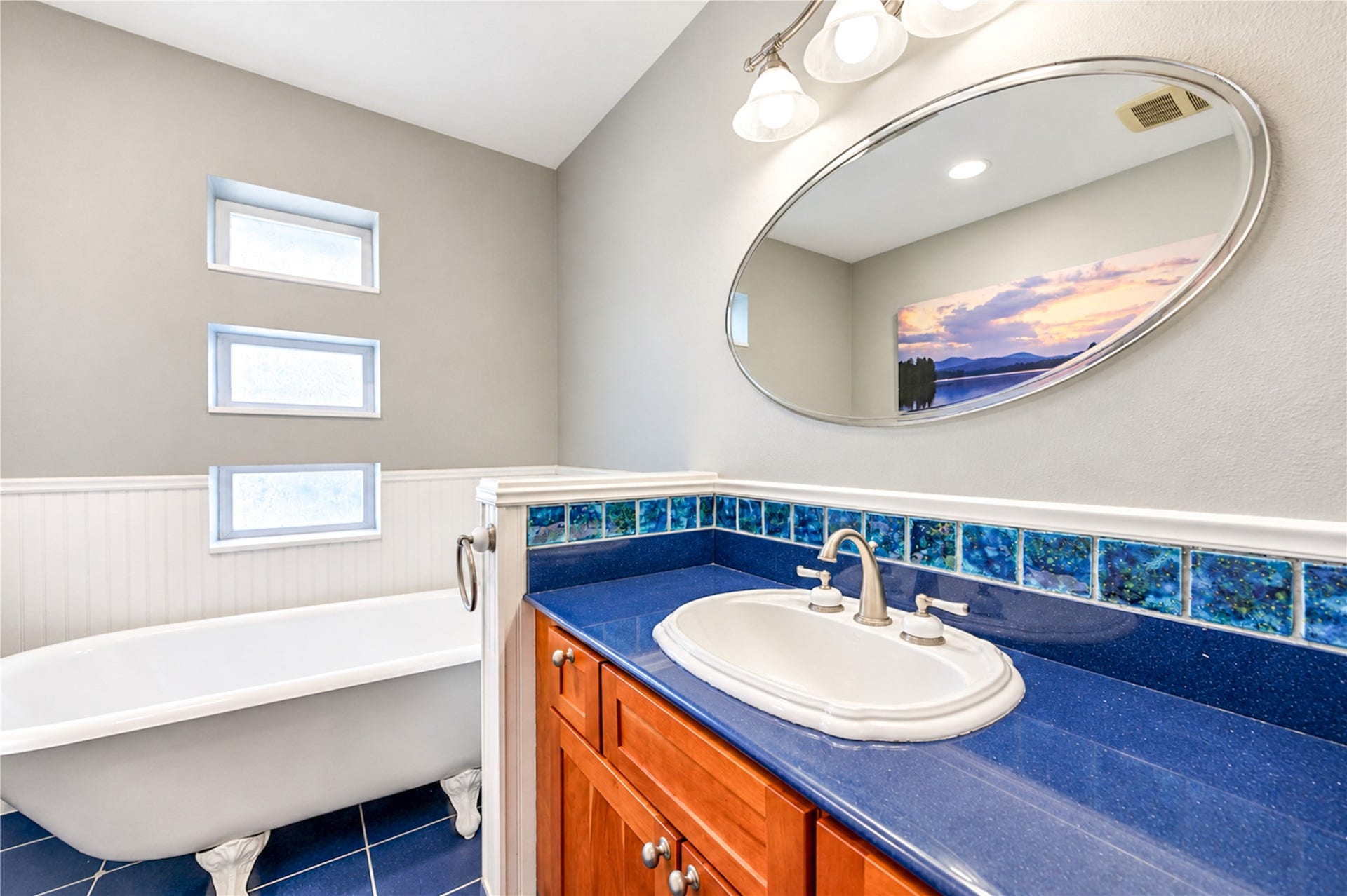 6211 Grovewood Lane, Houston, TX 77008 A classic clawfoot tub, rich blue countertop, decorative tile and a trio of accent windows give this charming bathroom distinctive character.