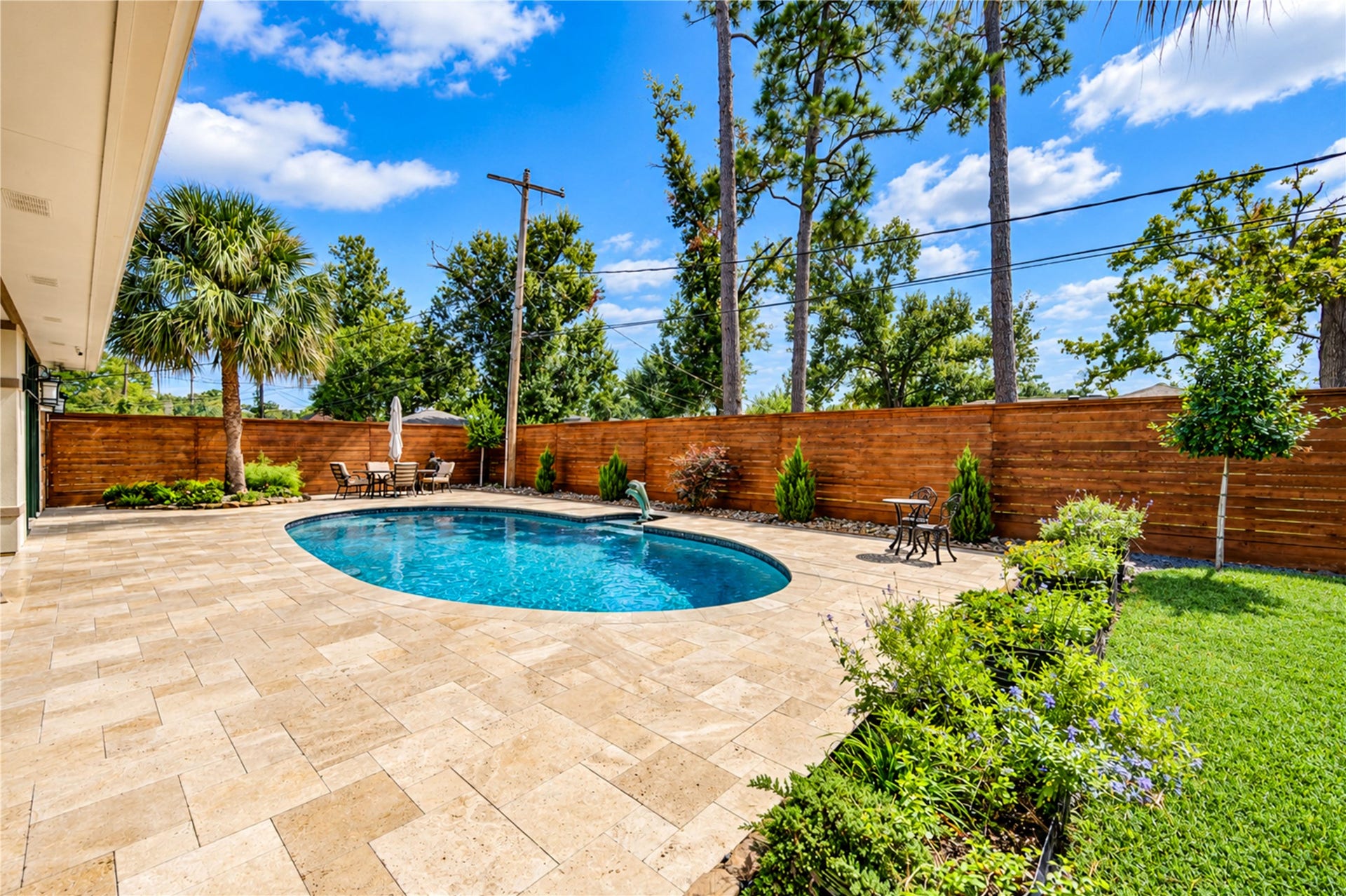 6211 Grovewood Lane, Houston, TX 77008 Palms, landscaped beds and a travertine terrace surround the pool along the rear of the home.