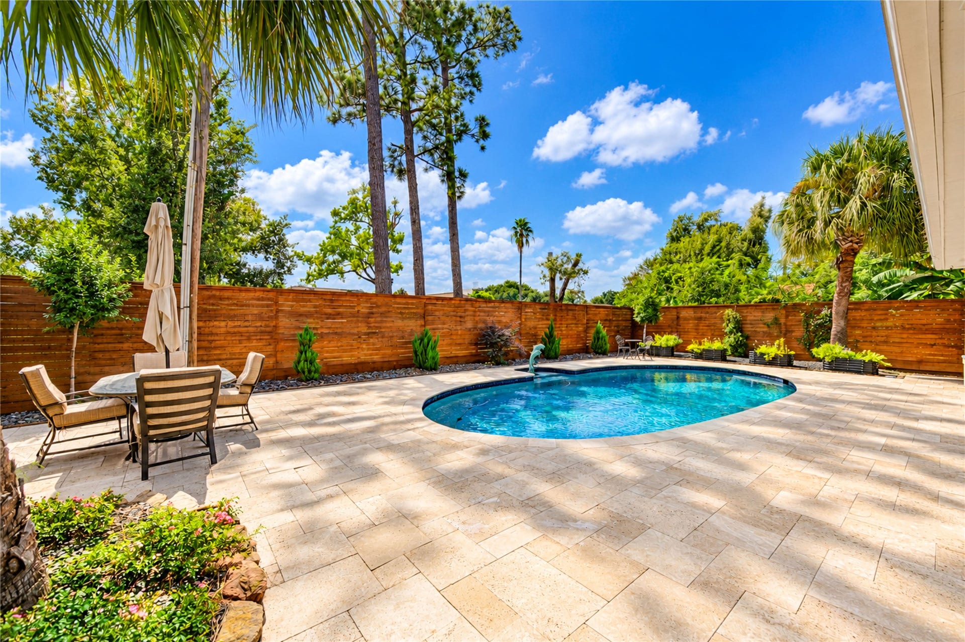6211 Grovewood Lane, Houston, TX 77008 A generous poolside terrace, mature palms and a horizontal wood privacy fence complete this inviting outdoor retreat.