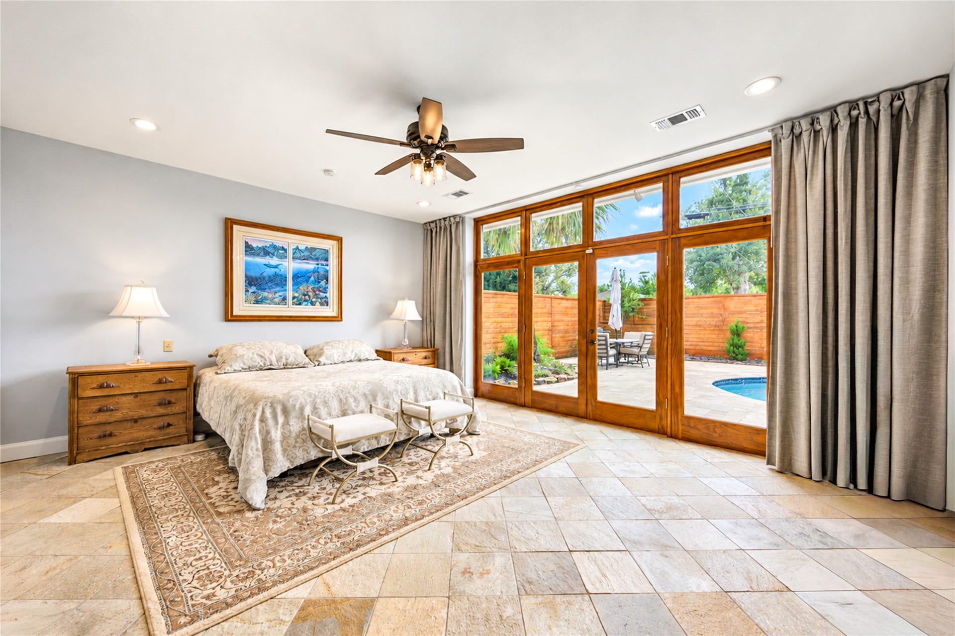 6211 Grovewood Lane, Houston, TX 77008 Glass doors and a wall of windows draw natural light into the primary suite and frame views of the pool.