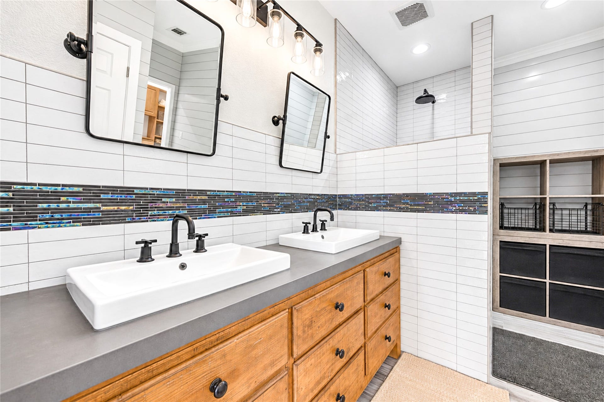 6211 Grovewood Lane, Houston, TX 77008 A dual vessel-sink vanity and framed mirrors anchor the primary bath, with the walk-in shower and built-in storage beyond.