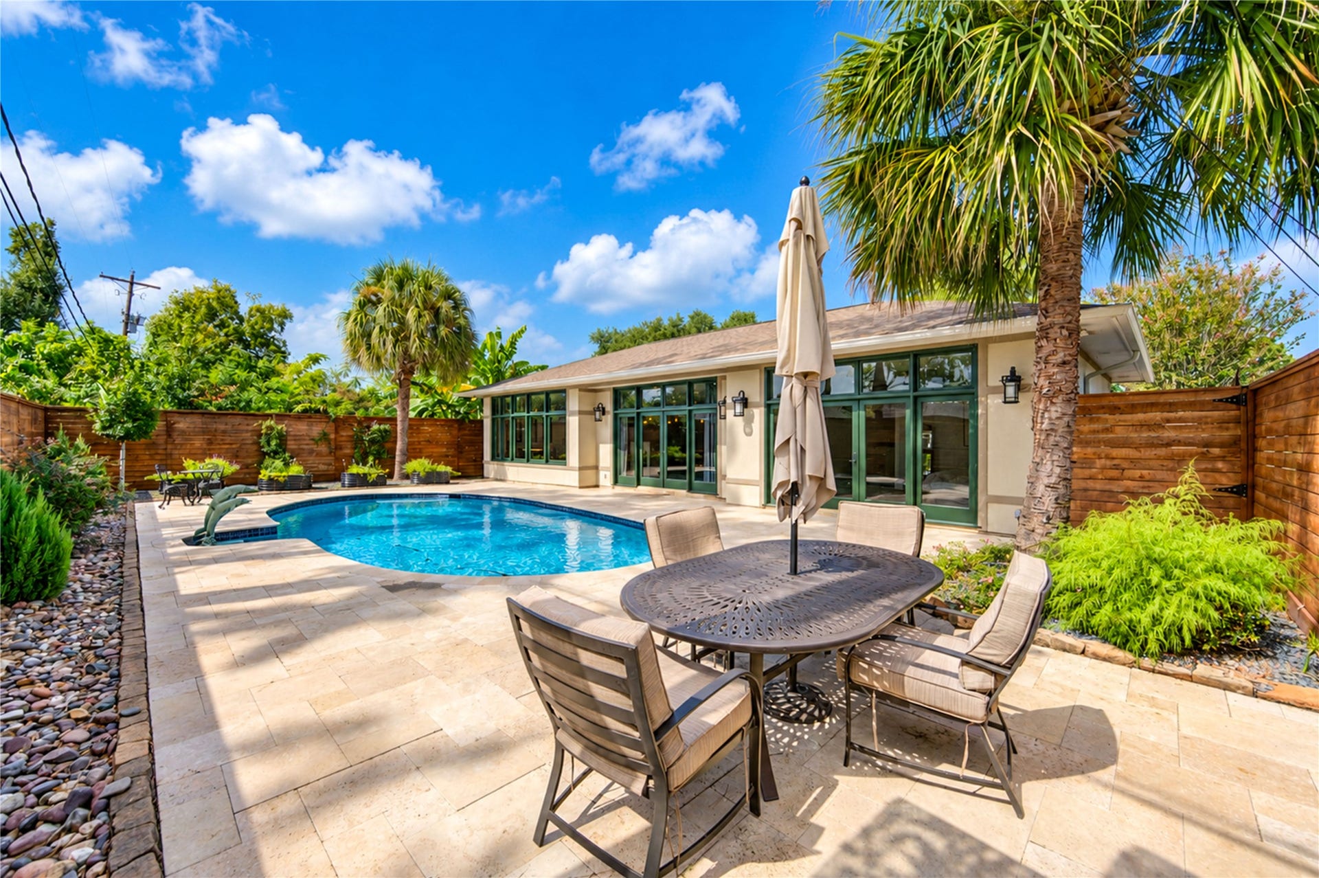 6211 Grovewood Lane, Houston, TX 77008 A travertine terrace with room for outdoor dining wraps the pool, with palms and wood fencing for privacy.