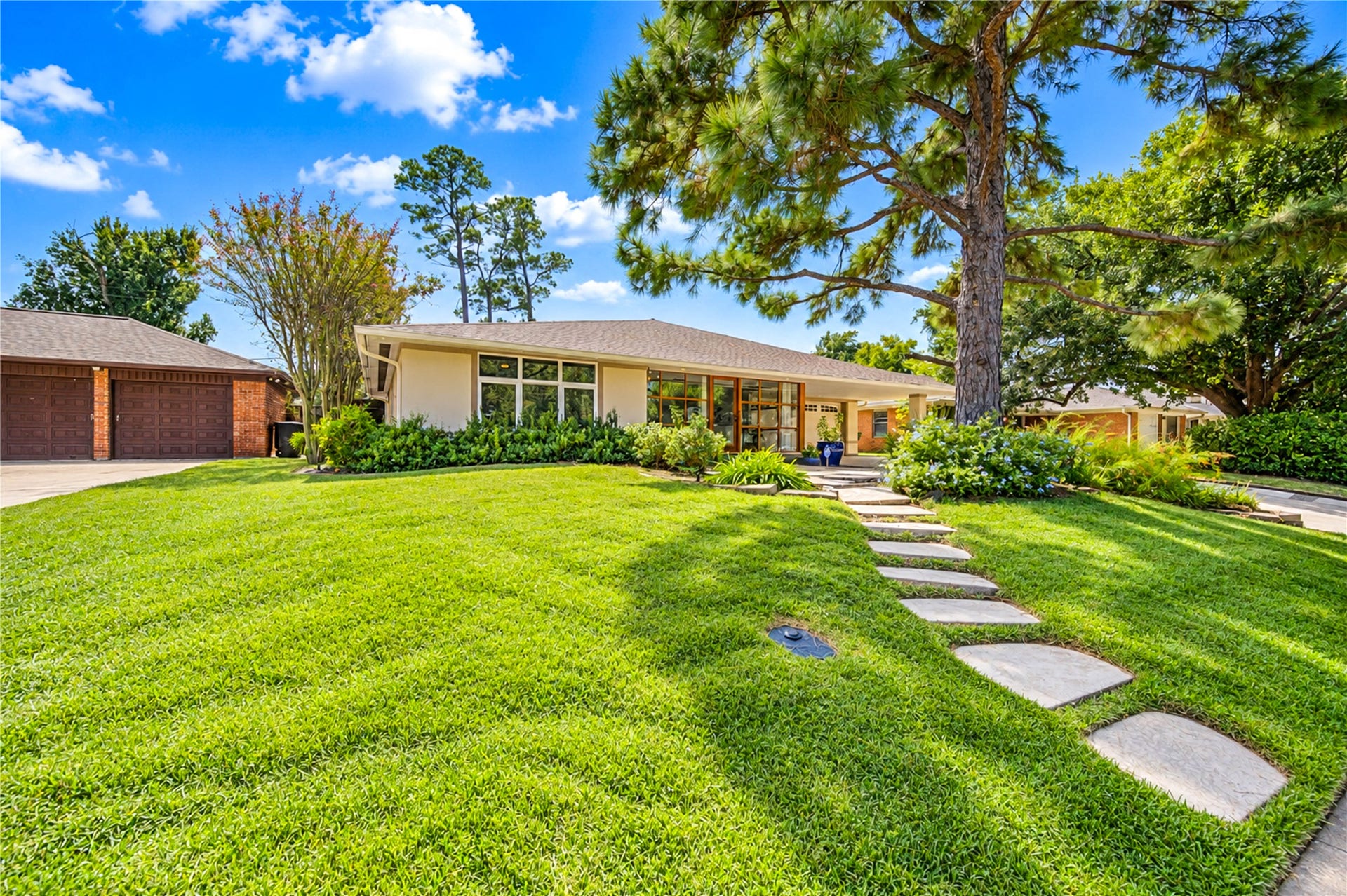 6211 Grovewood Lane, Houston, TX 77008 A glass-and-wood entry and a geometric concrete-and-gravel drive set an architectural tone beside the attached garage.