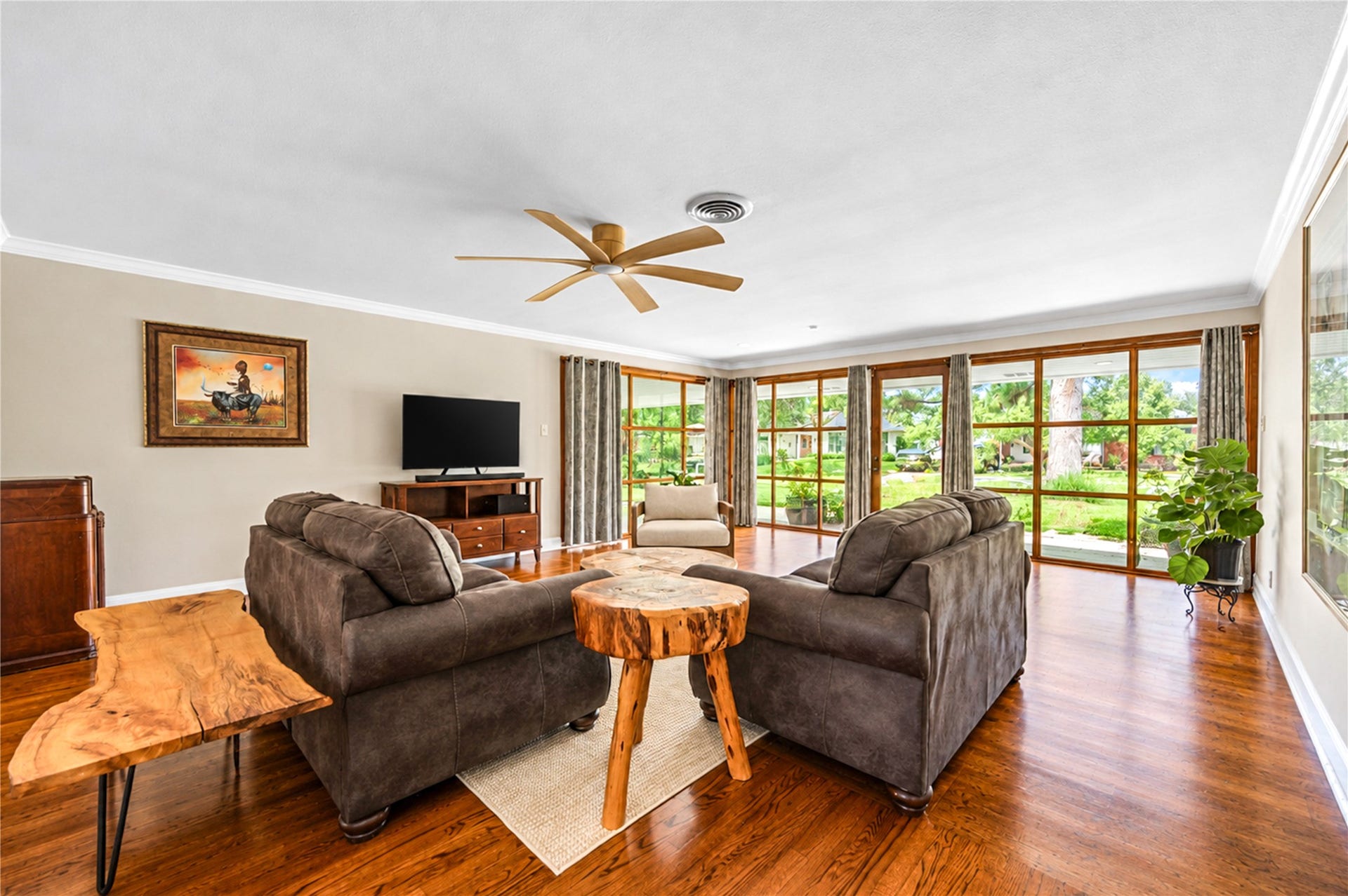 6211 Grovewood Lane, Houston, TX 77008 A wall of wood-framed windows frames garden views and fills the living room with natural light above rich hardwood flooring.