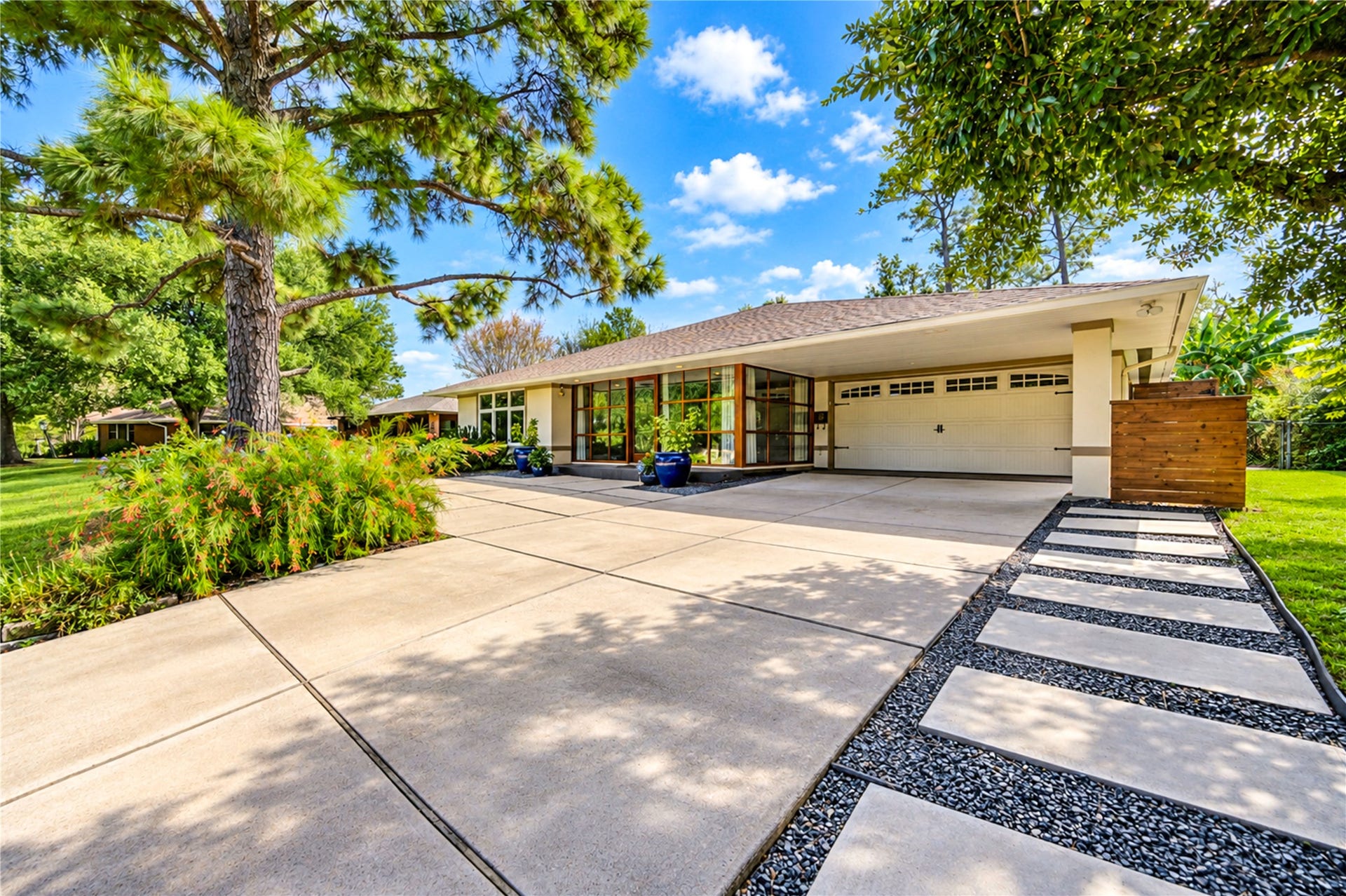 6211 Grovewood Lane, Houston, TX 77008 A low roofline, wood-framed glass entry and stepping-stone path set a clean mid-century tone at the front of the home.