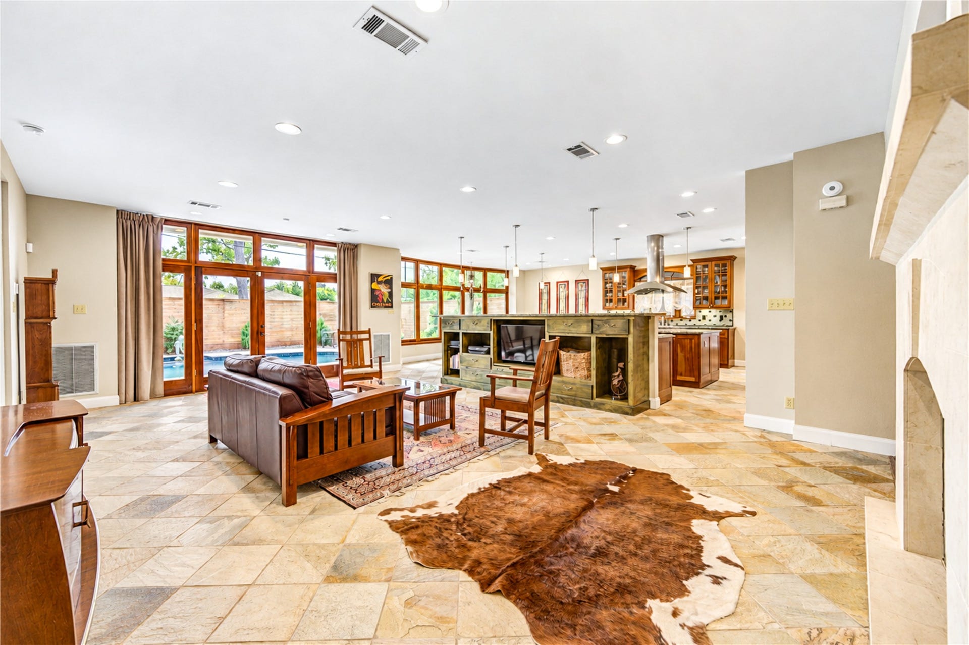 6211 Grovewood Lane, Houston, TX 77008 Stone flooring flows through the open family room and kitchen, with the fireplace on one side and wood-framed glass doors to the pool on the other.