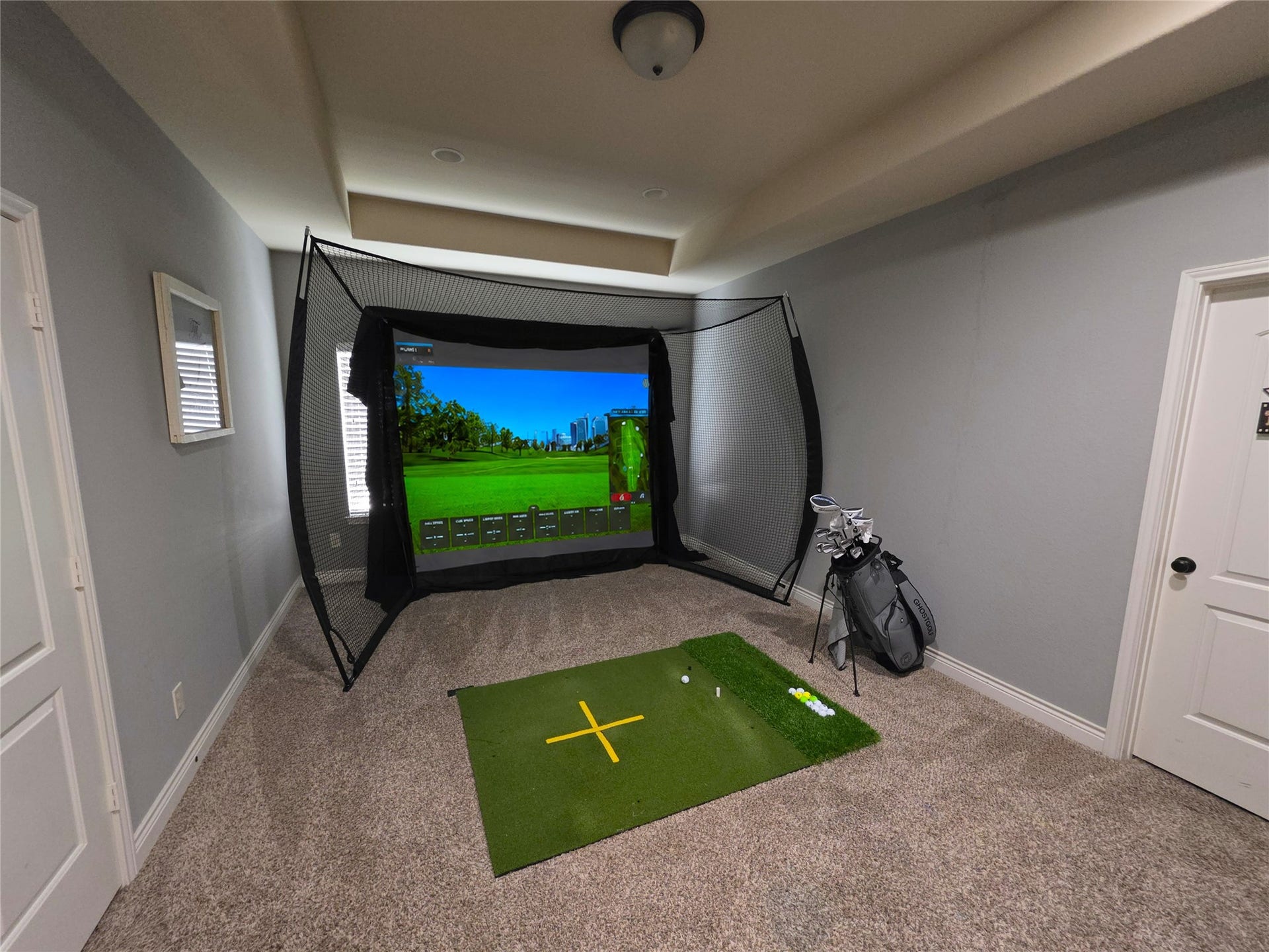 9723 Painted Stone Court, Cypress, TX 77433 Elevate your leisure time in this spacious game room, featuring a golf simulator complete with a projector and high ceilings.