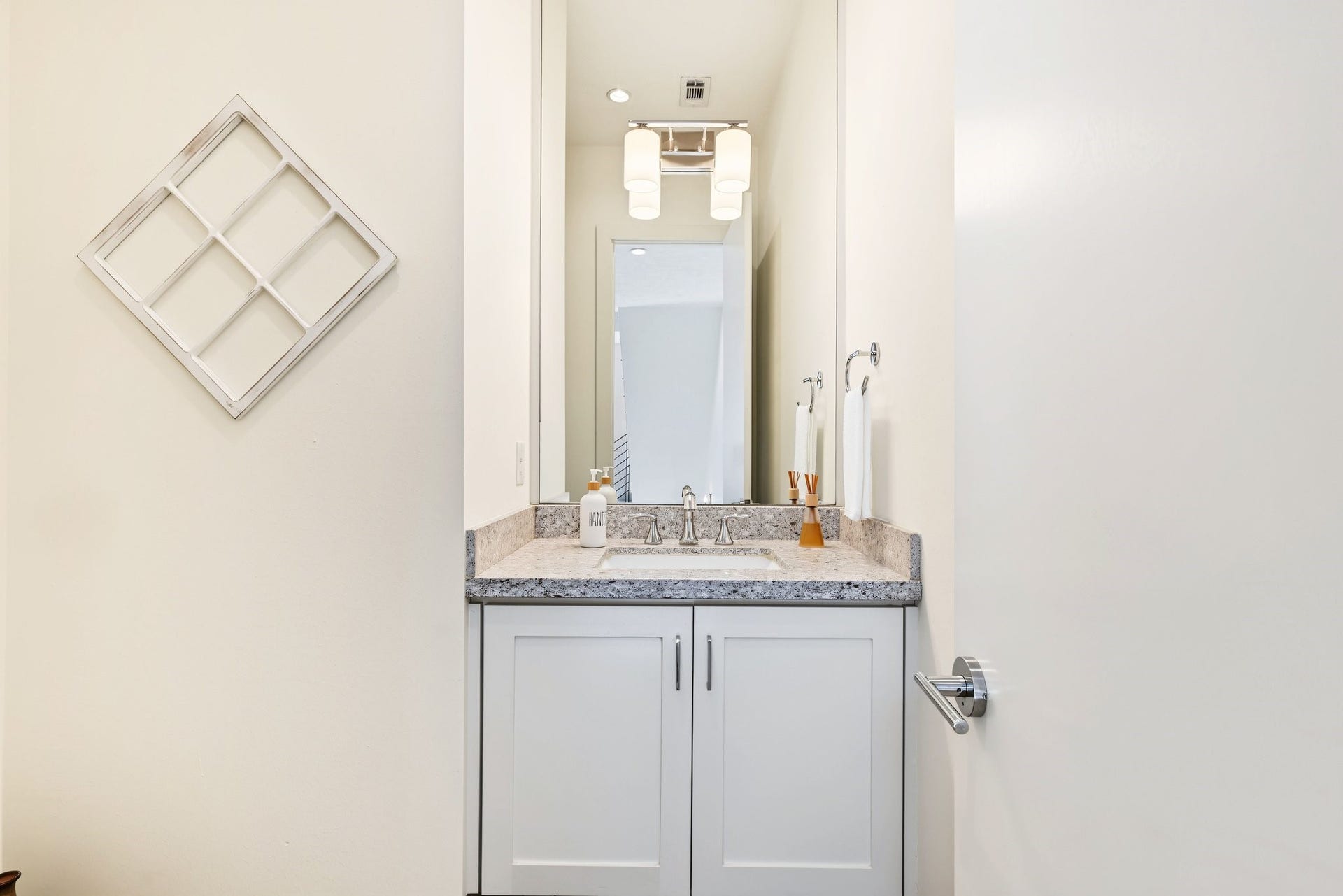 Welcome guests with a powder room that extends the homes crisp, modern aesthetic into every detail. Centered around a marble-topped Shaker-style vanity and an expansive frameless mirror, this bright and polished space is conveniently situated just off the main living areas.