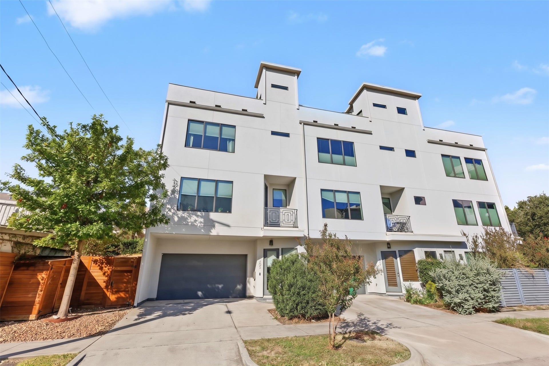 The exterior makes an immediate visual statement with its dark-framed window grid, featuring a balanced combination of wide picture windows, multi-pane casements, and narrow clerestory transoms thoughtfully arranged across every floor to bring in natural light.