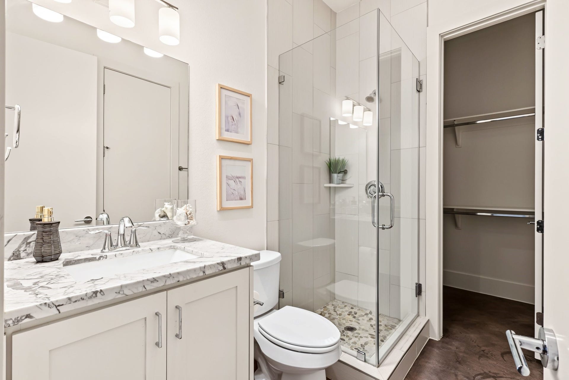 A veined marble countertop and crisp white Shaker-style vanity serve as the refined focal point of this secondary bath. Outfitted with an undermount sink, gleaming chrome plumbing fixtures, and an expansive frameless mirror, the space pairs timeless sophistication with everyday utility.
