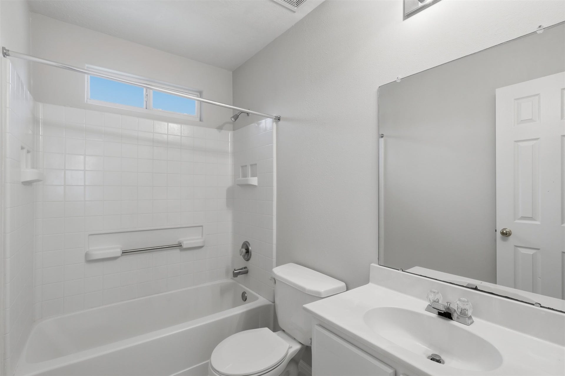 Bright upper-level secondary bath equipped with elegant marble-look tile flooring, a tub/shower combination, white vanity, and a high transom window that lets in natural light while maintaining privacy.