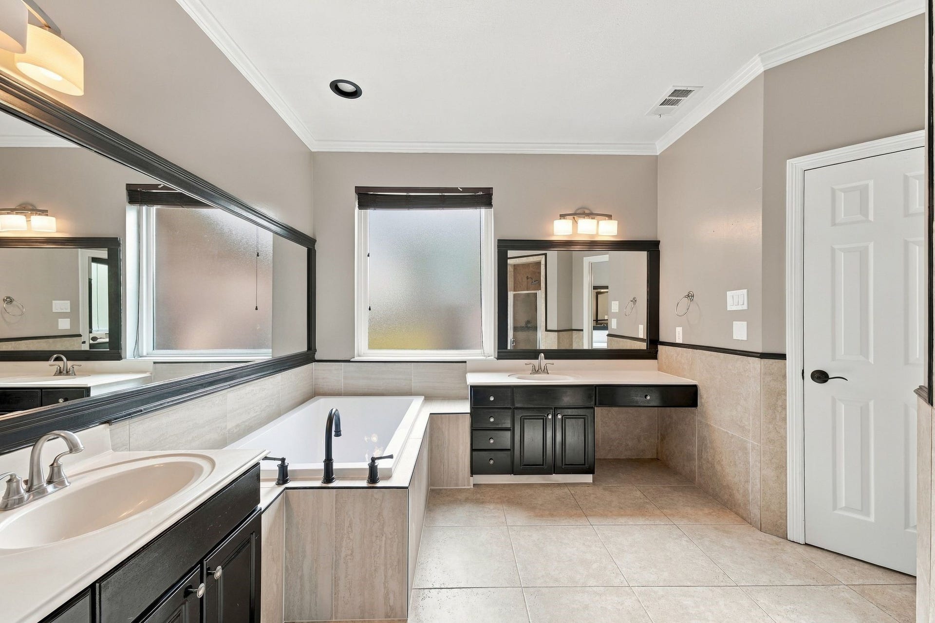 1065 Heritage Lane, Conroe, TX 77304 The primary bath has updated framed mirrors and lighting, a recently replaced soaking tub, gorgeous tile floors and TWO sinks!