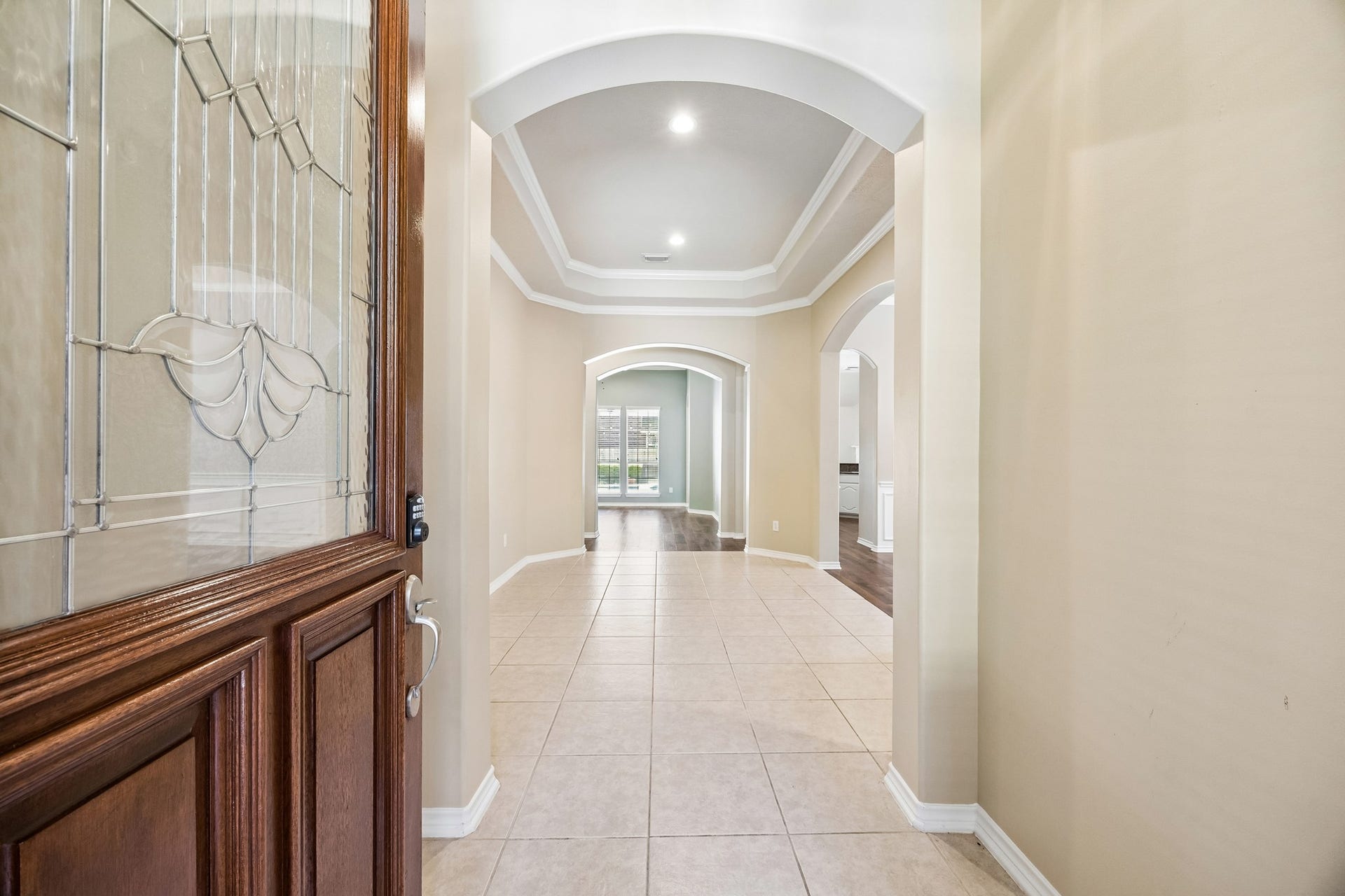 Beautiful leaded glass front door adds character and elegance to the entry, while the long hallway, graceful arched openings, and thoughtful one-story layout create an inviting flow throughout the home.