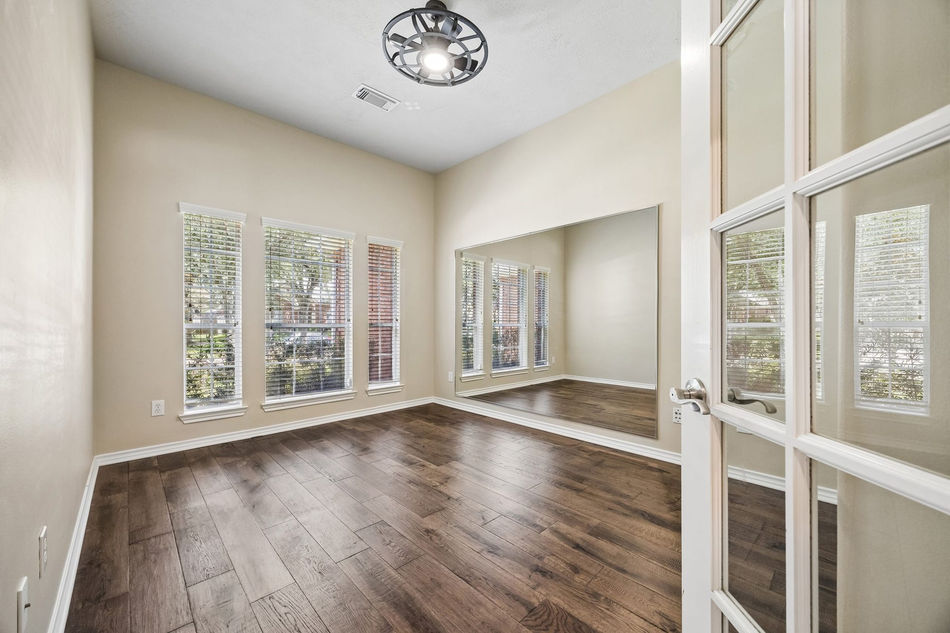 Private study with French doors, built-in shelving, engineered hardwood flooring, and large windows that fill the room with natural light. A versatile space ideal for a home office, library, or quiet sitting room.